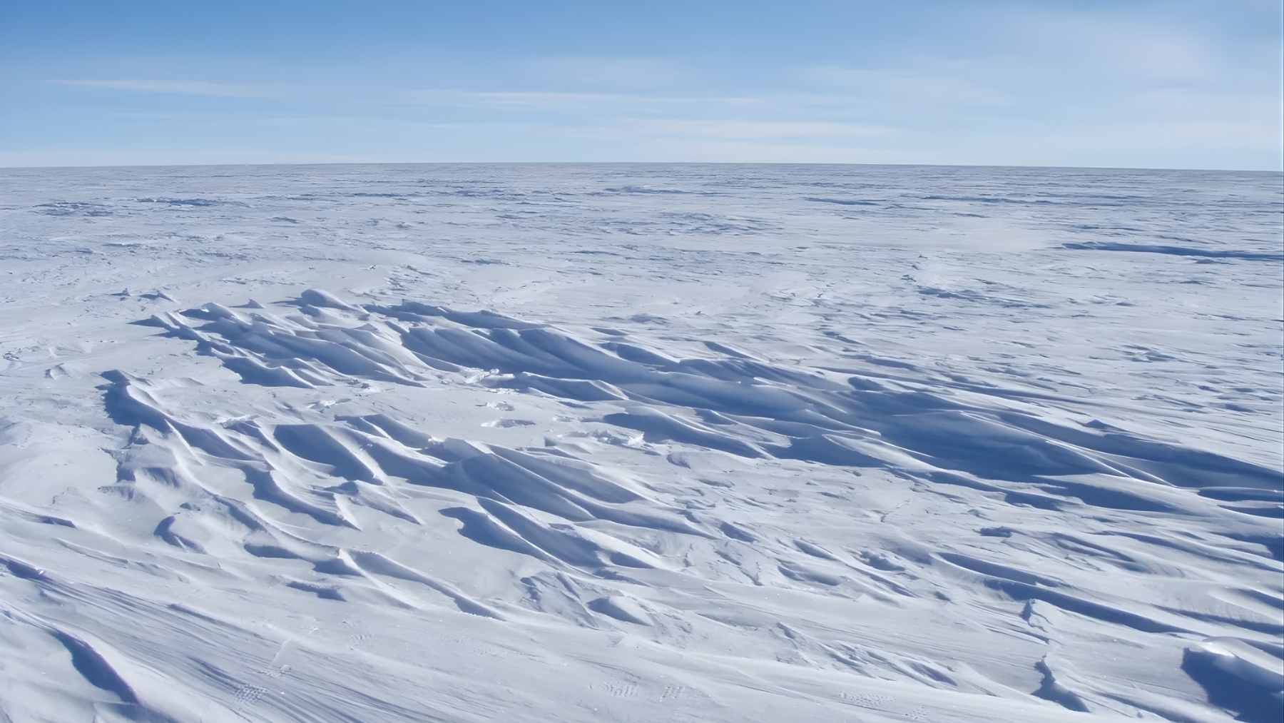 Snow-covered Antarctic ice sheet under a clear blue sky, as scientists report the ozone hole closed unusually early in 2025.