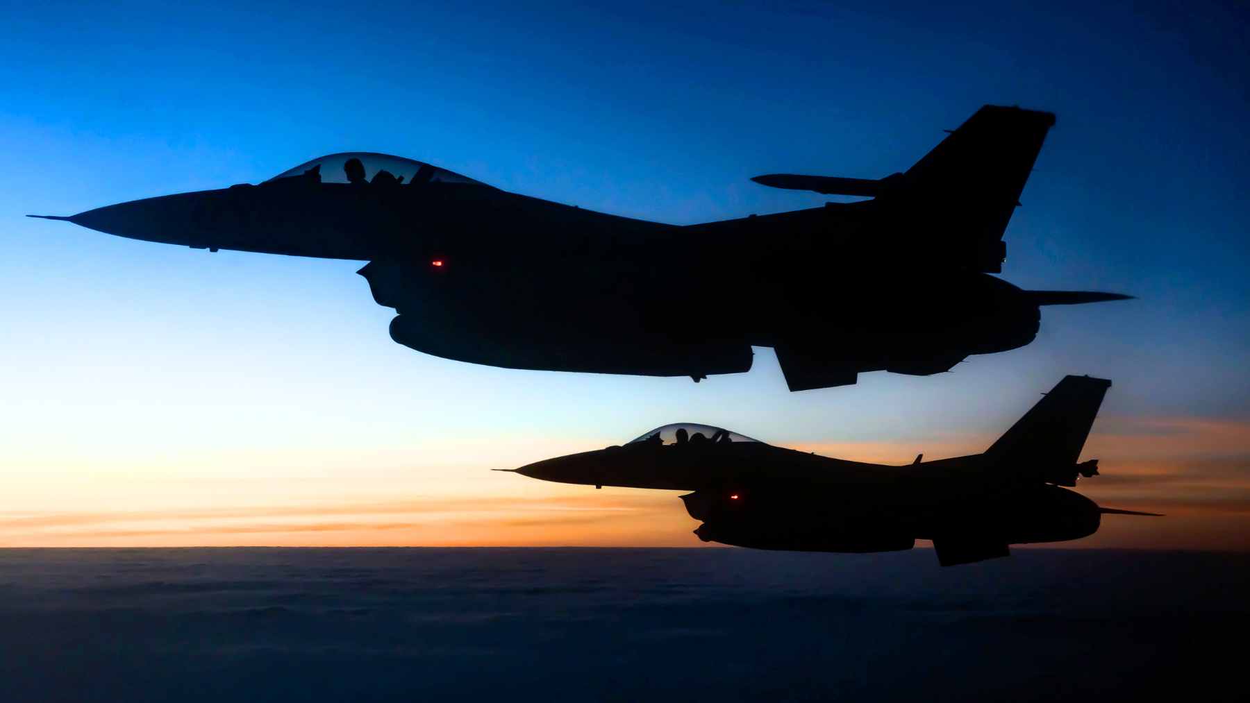 Two U.S. Air Force F-16 fighter jets fly in formation at dusk