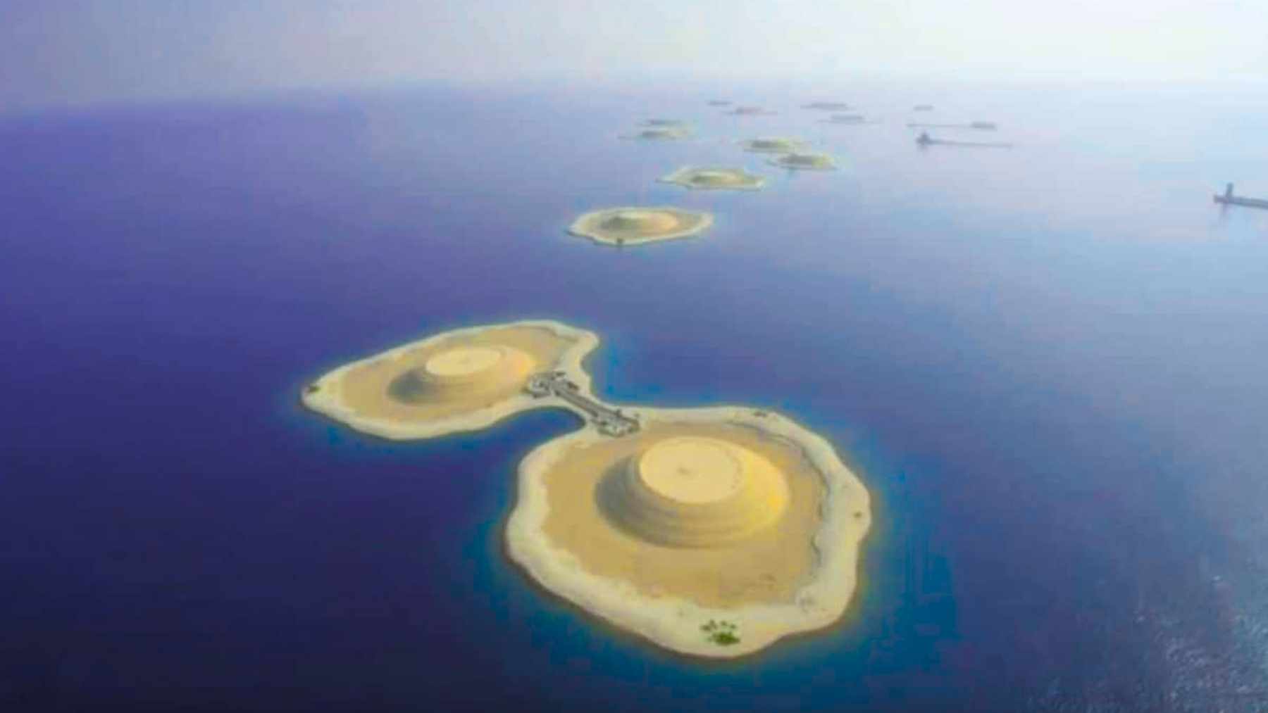 Aerial view of sand-filled artificial islands linked by a narrow causeway, built by dredging in the South China Sea.