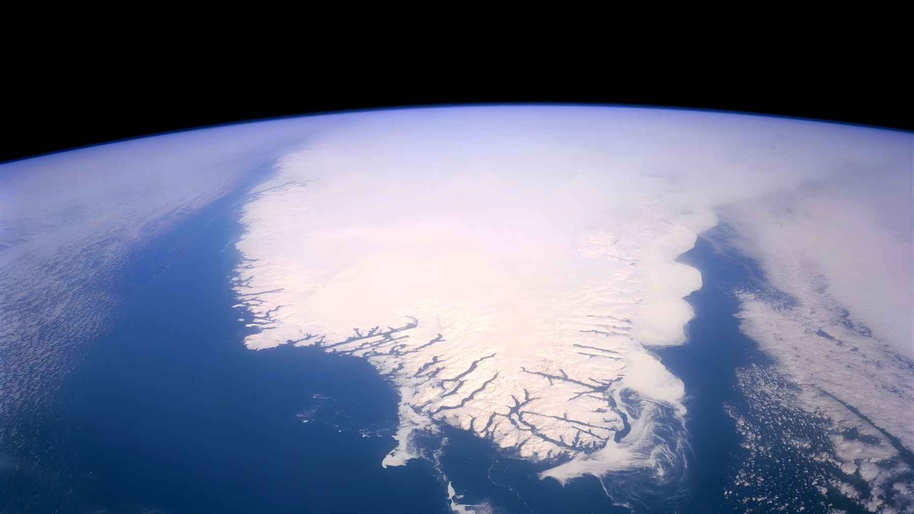 Greenland’s ice sheet and coastline seen from above, highlighting the Arctic landscape where critical minerals and hydrocarbons may lie beneath the ice.
