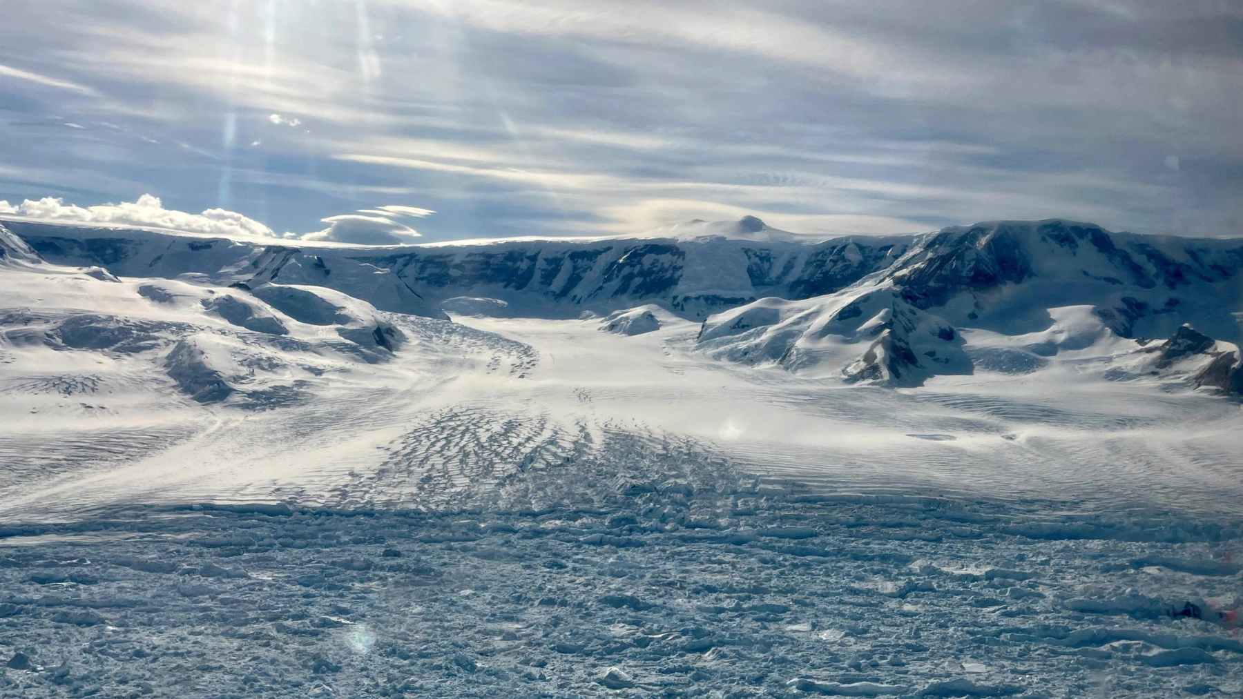 A wide view of the Hektoria Glacier terminus on the Antarctic Peninsula, with fractured sea ice in the foreground.