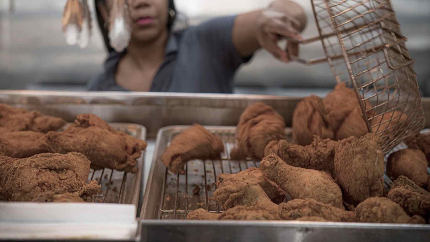 Worker loads fried chicken into trays at Frenchy’s in Houston, where two locations were recently deauthorized