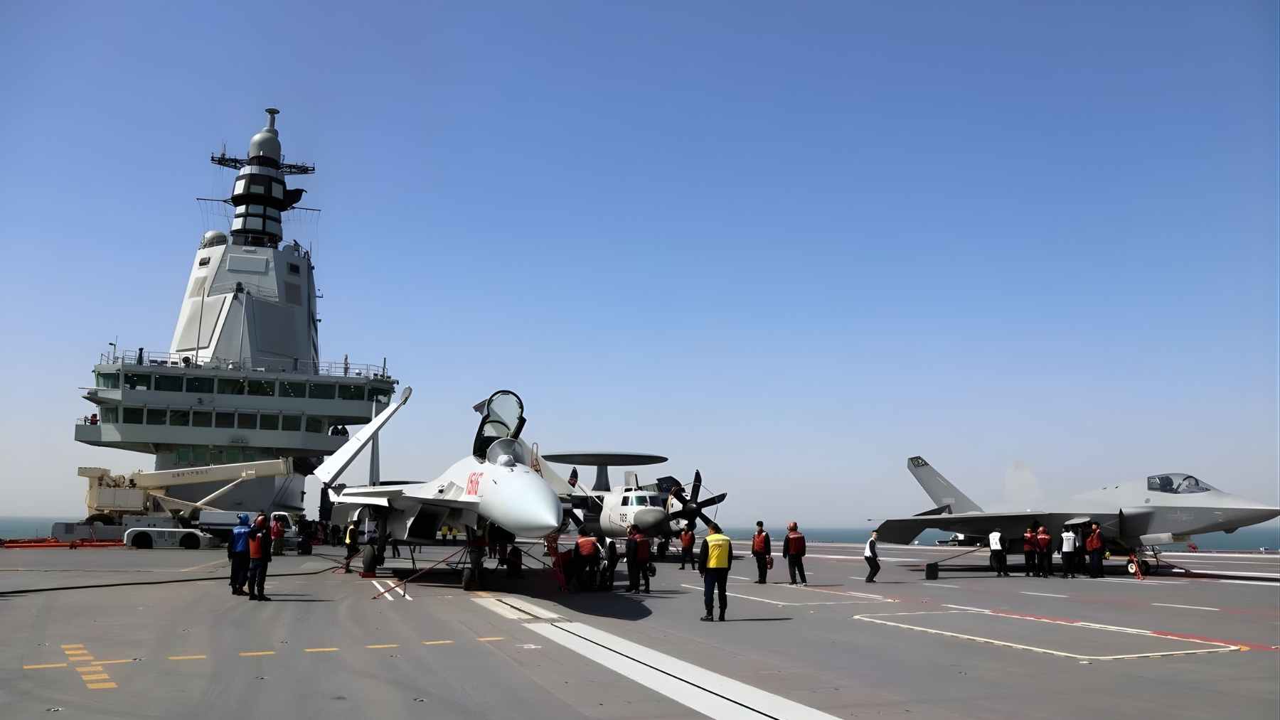 Chinese aircraft carrier flight deck with fighter jets and crew, highlighting the emissions footprint of carrier aviation