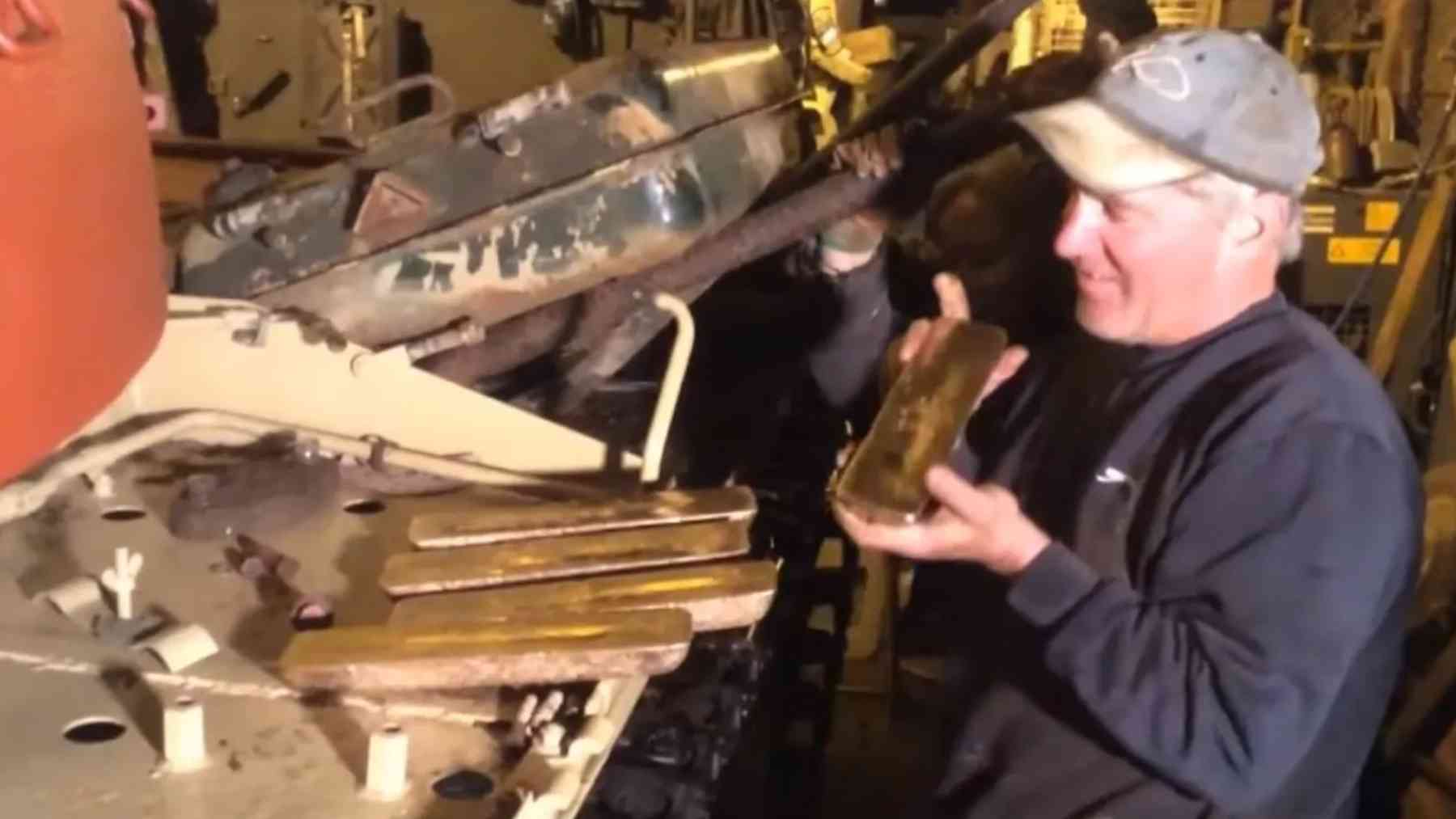 Mechanic holding gold bars discovered inside an old Iraqi Army Type 69 tank purchased online