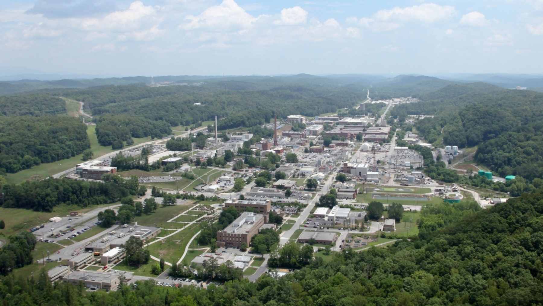 Aerial view of Oak Ridge National Laboratory in Tennessee, showing research buildings and facilities surrounded by forested hills.