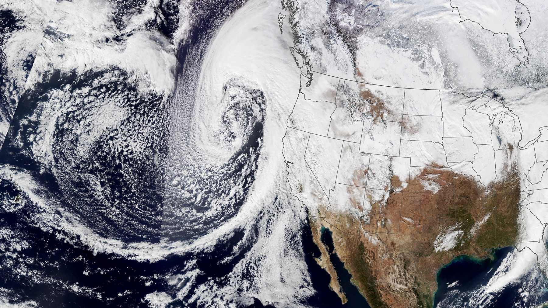 Satellite view of a powerful Pacific storm aimed at the U.S. West Coast, with thick cloud bands signaling heavy mountain snow.