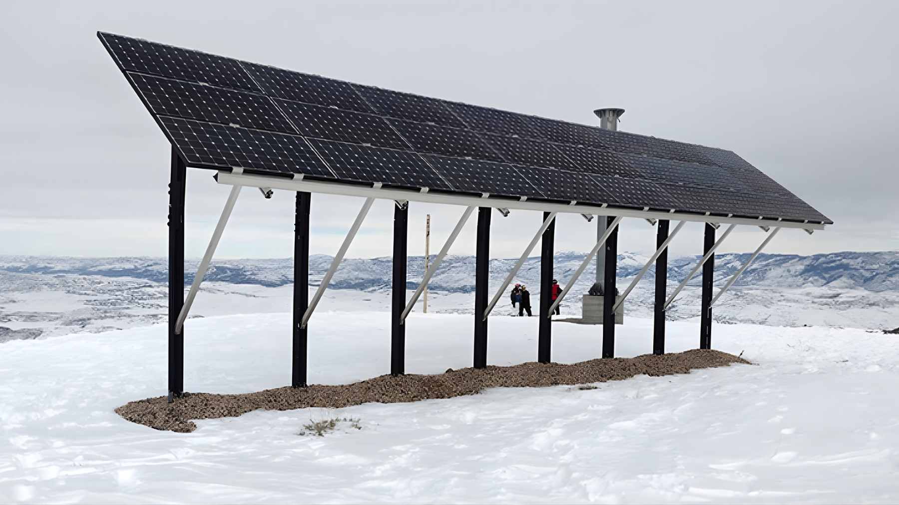 Solar panels mounted on a raised frame in a snowy landscape, showing a winter solar installation under overcast skies.
