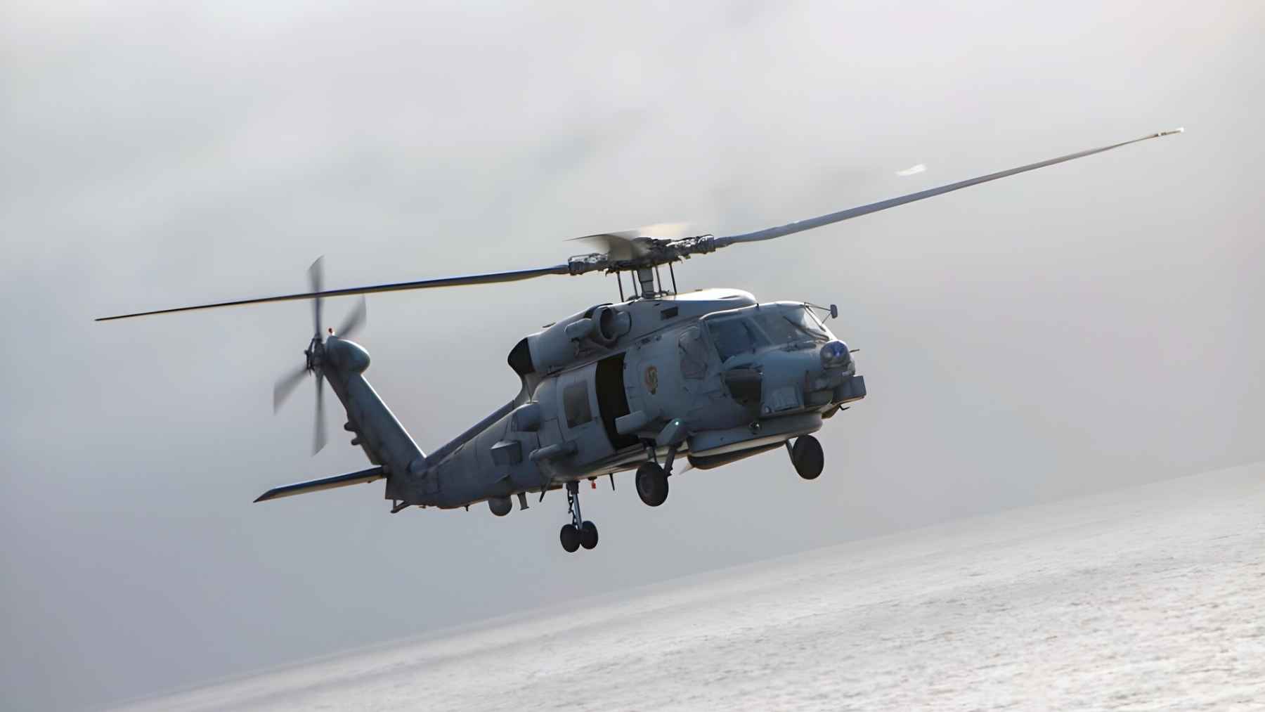 U.S. Navy MH-60R Sea Hawk helicopter flying over the ocean during carrier operations