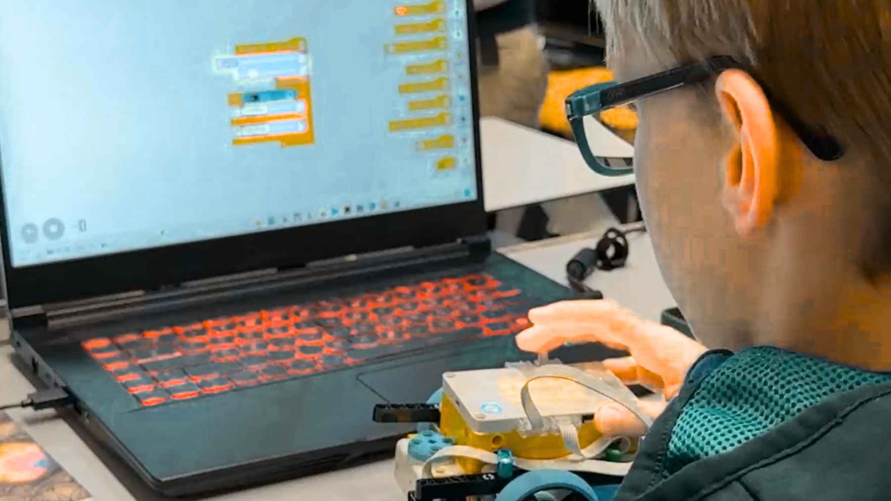 10-year-old boy in Rostock programming a small educational robot with block-based code on a laptop during a MikroMINT technology workshop