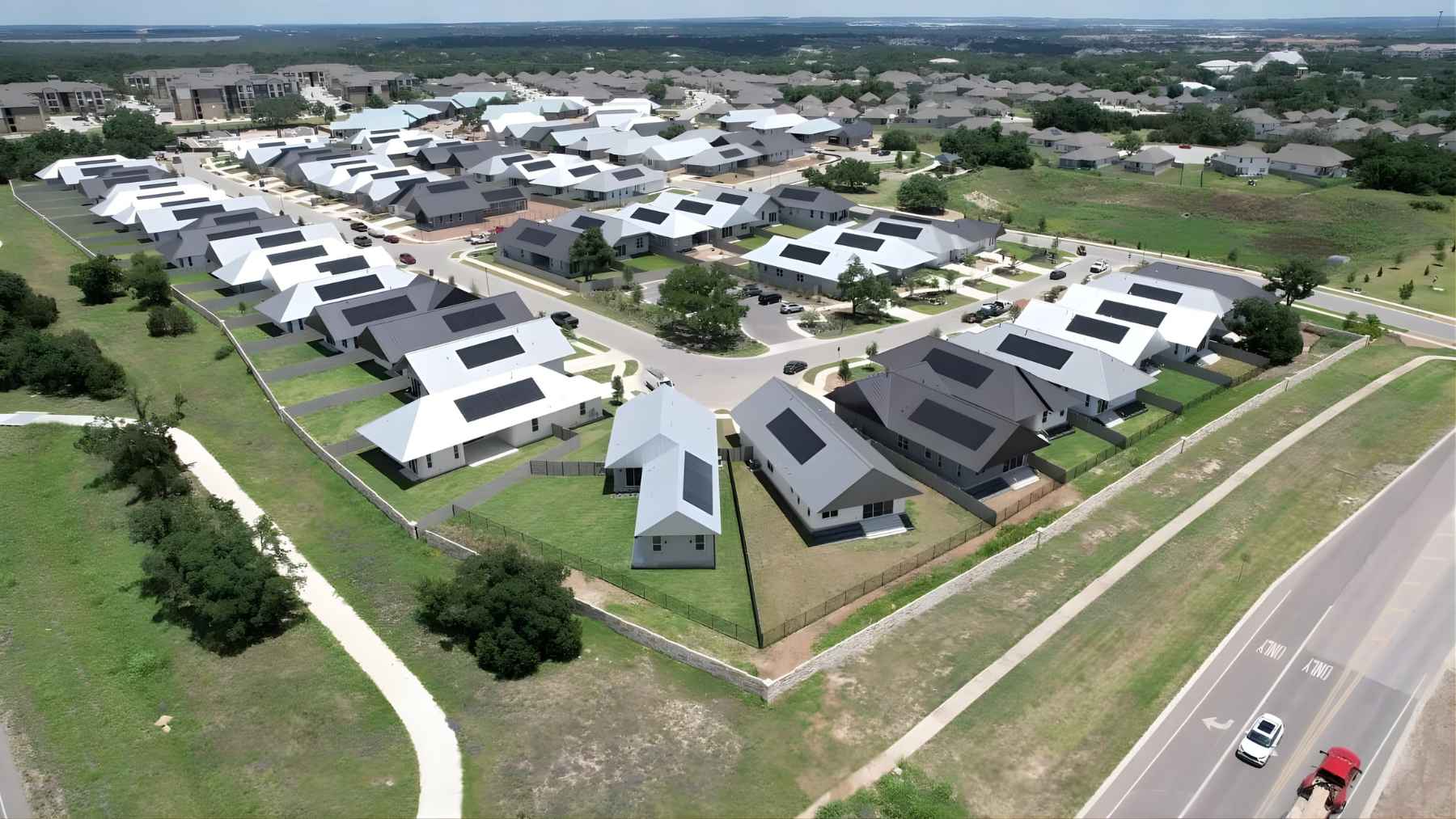 Aerial view of a new neighborhood of modern homes with rooftop solar panels, illustrating fast, tech-driven construction.