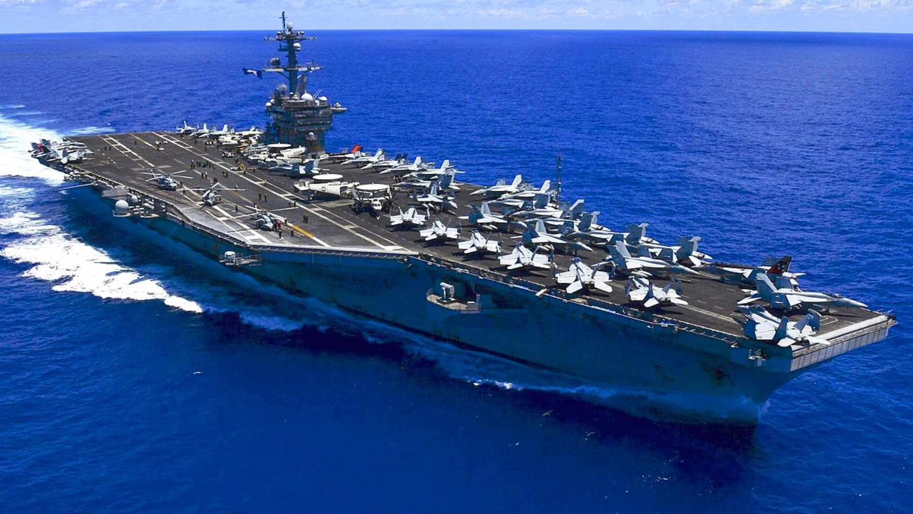 U.S. Navy aircraft carrier steaming through the South China Sea with fighter jets lined up on the flight deck.