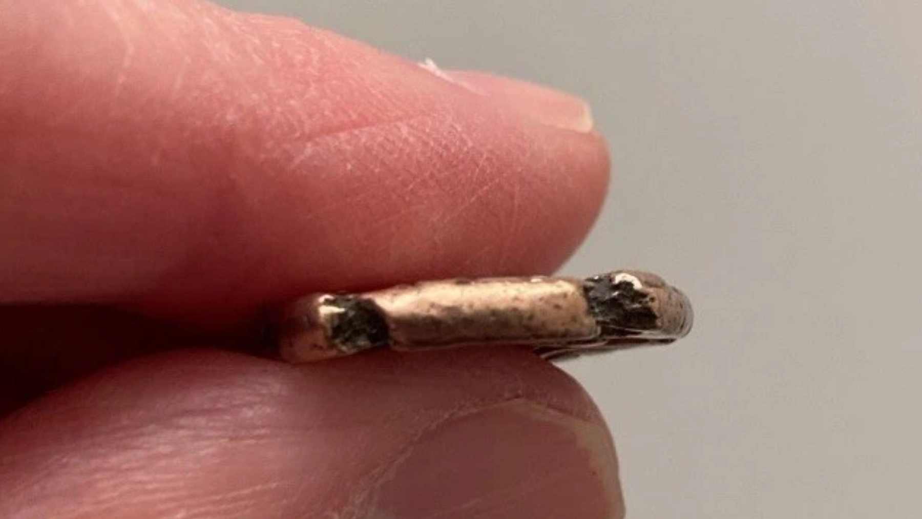 Close-up of an ancient coin edge held between fingers from the Anglesey Iron Age gold hoard, later declared treasure.