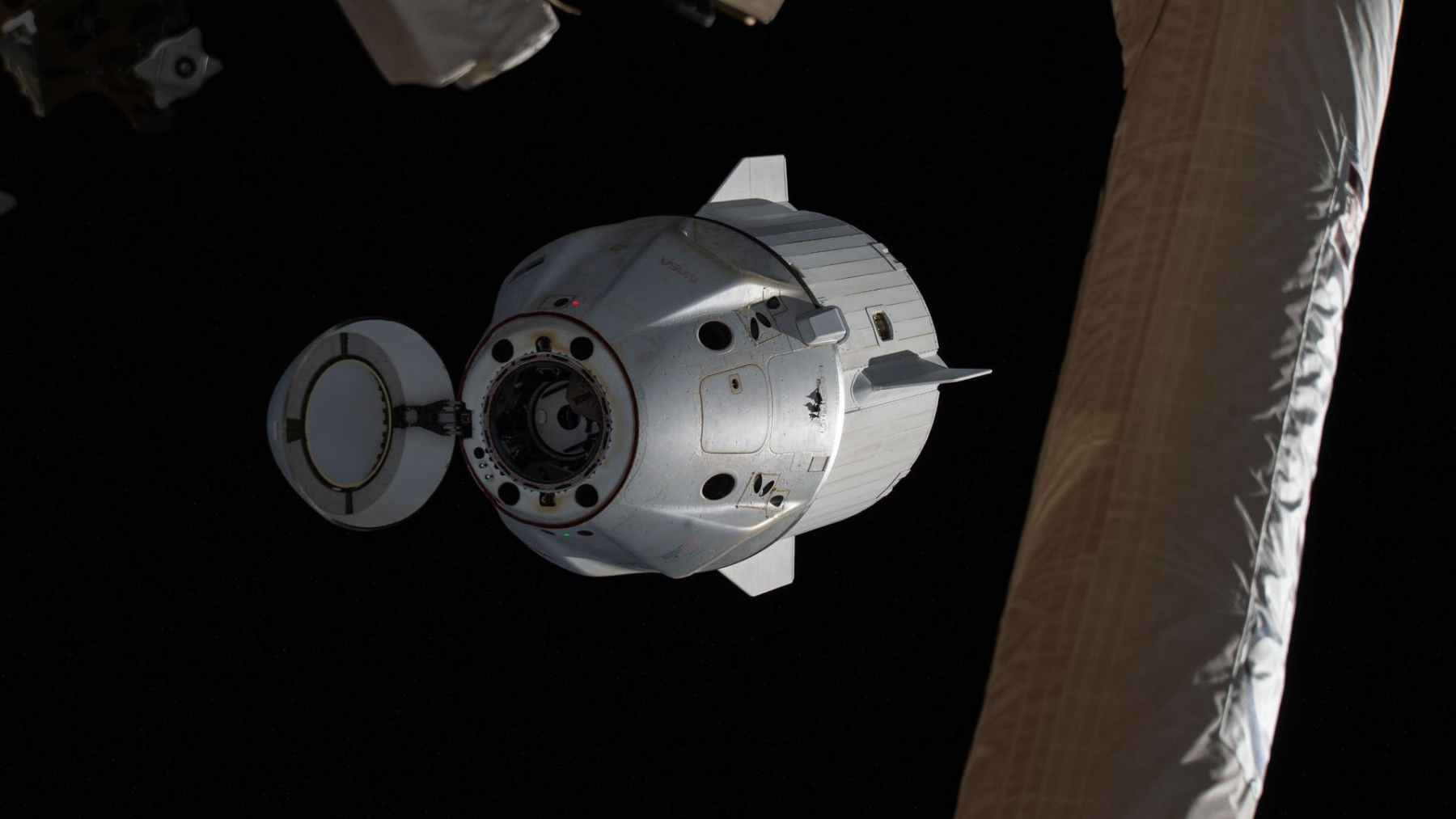SpaceX Crew Dragon capsule approaches the International Space Station in orbit, with its hatch open during a docking sequence.