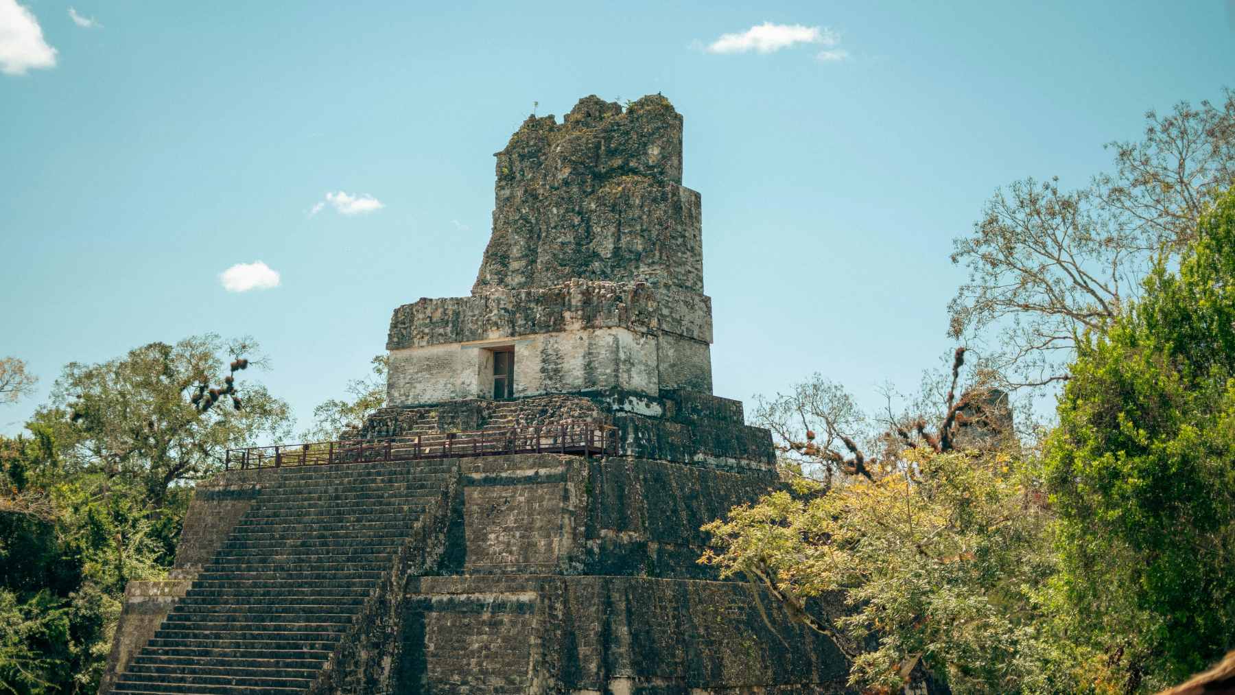 A Maya temple rises above jungle trees in Guatemala, reflecting the civilization whose decline is being reexamined through lake sediments.