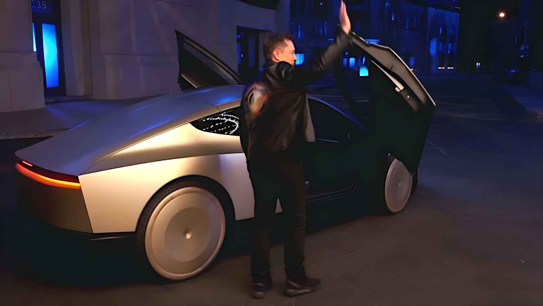 Elon Musk stands beside Tesla’s Cybercab concept vehicle at night with the door open, highlighting delays in robotaxi production.