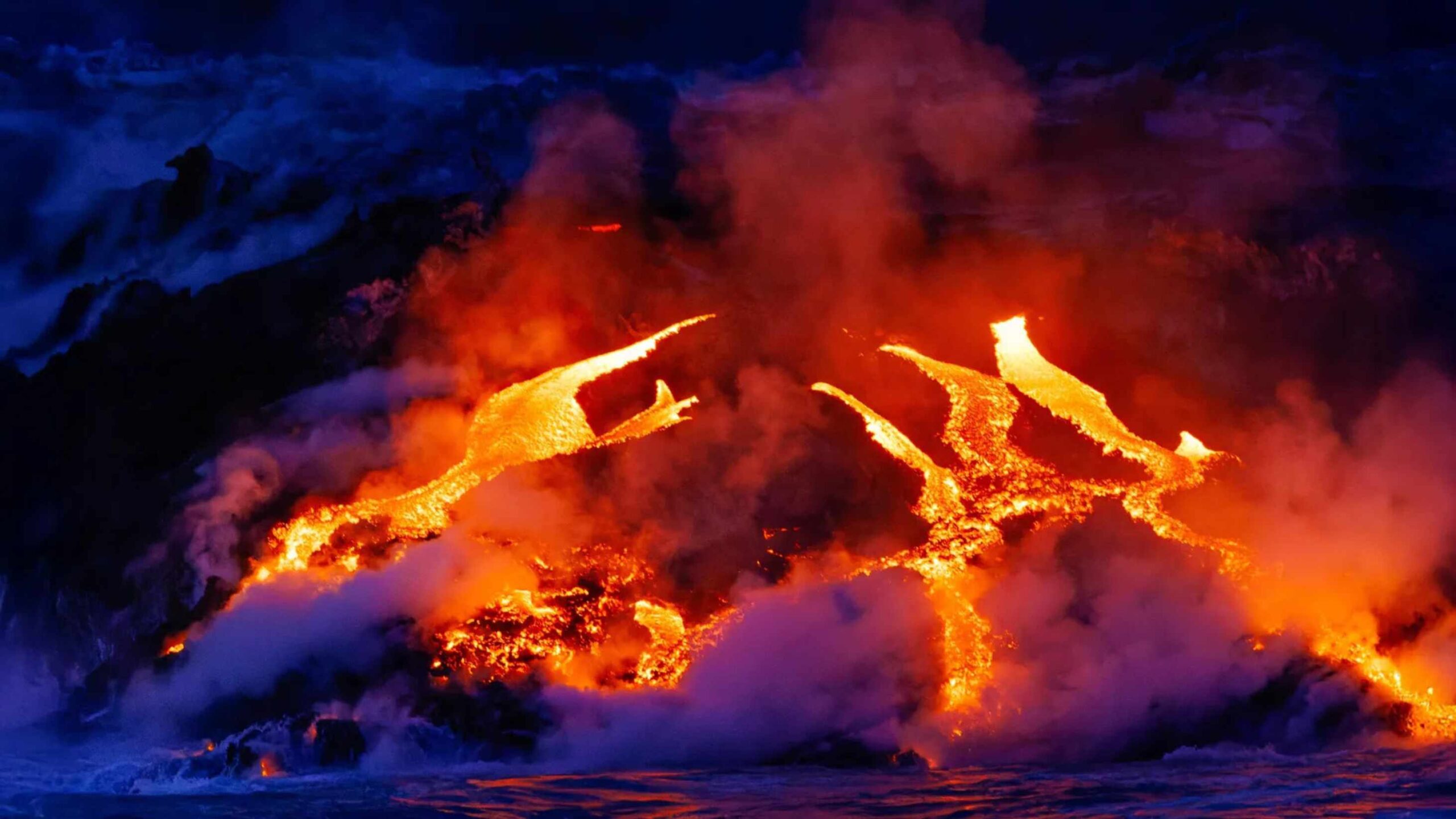 Glowing lava flows into the ocean during an ocean island eruption, illustrating how deep mantle processes can fuel volcanism and release CO2.