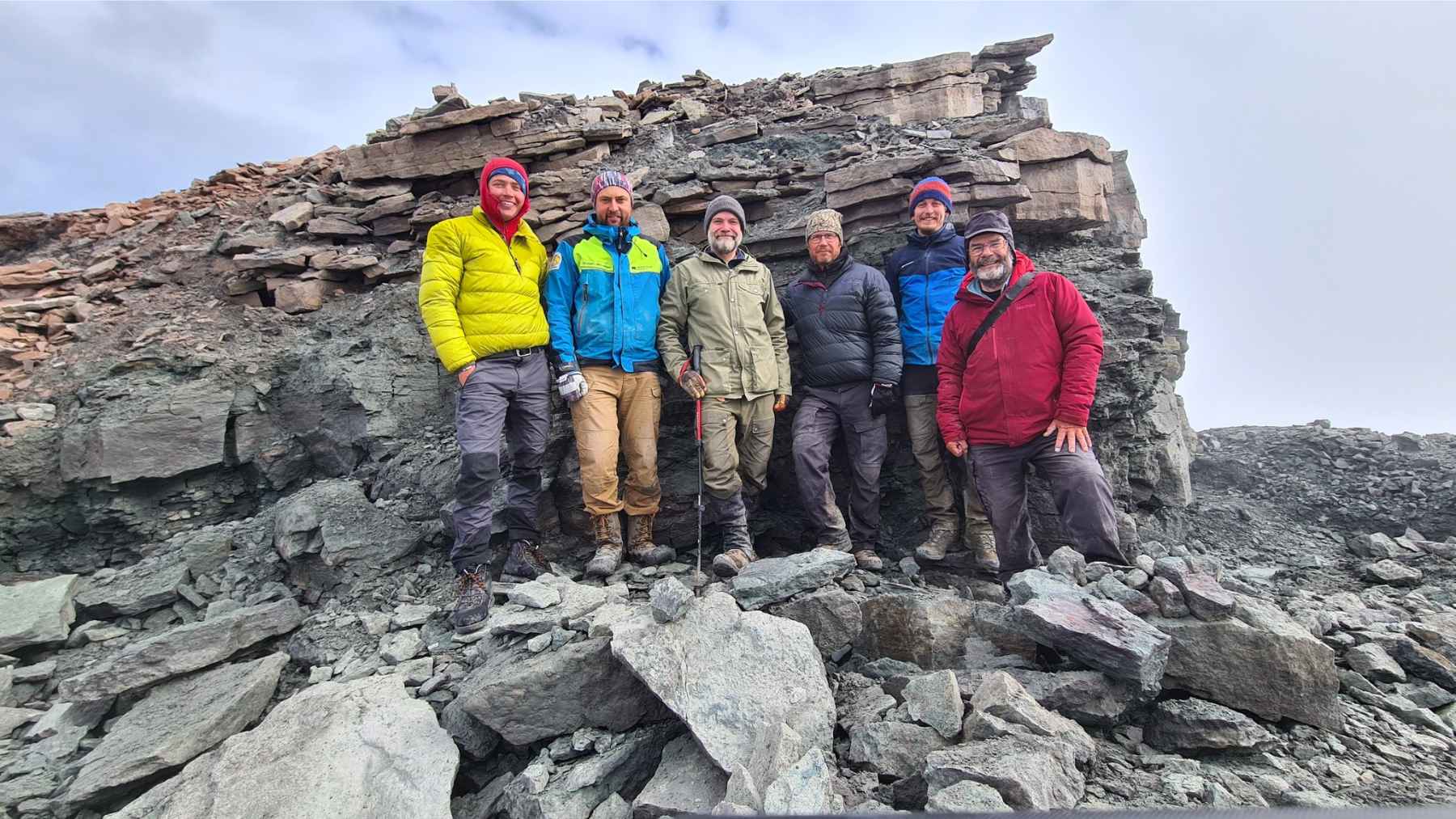 Researchers stand on a rocky slope in northeast Greenland after a fossil field expedition on Ymer Island near Mount Celsius.