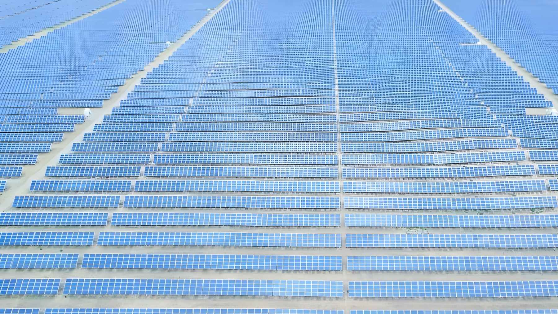 Aerial view of a vast solar farm in Qinghai, China, with rows of photovoltaic panels stretching across desert land.