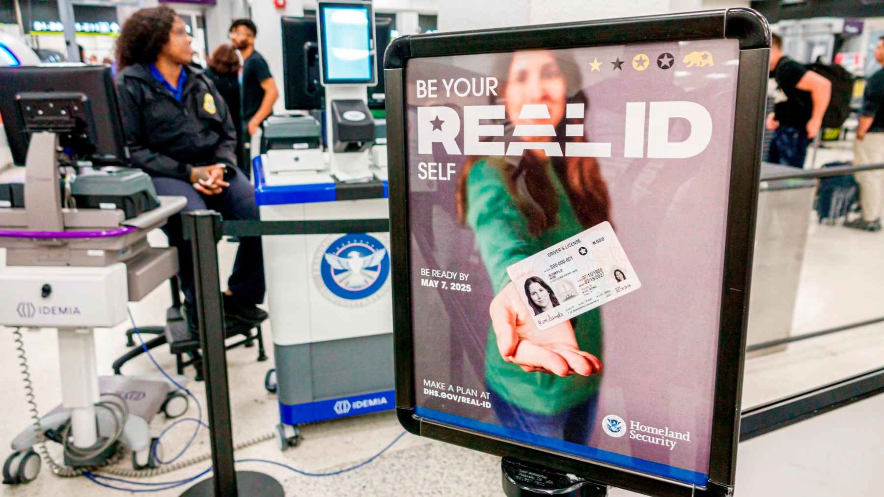 A TSA officer helps travelers at an airport security checkpoint, highlighting new ID rules and a ConfirmID fee for passengers without REAL ID.
