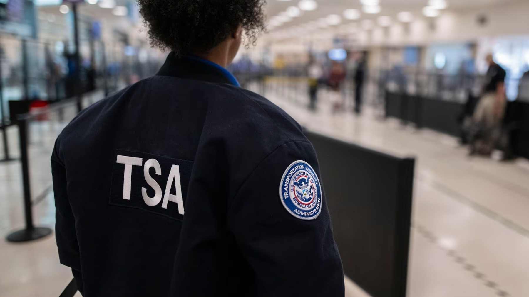 TSA officer monitoring security lines at a U.S. airport checkpoint