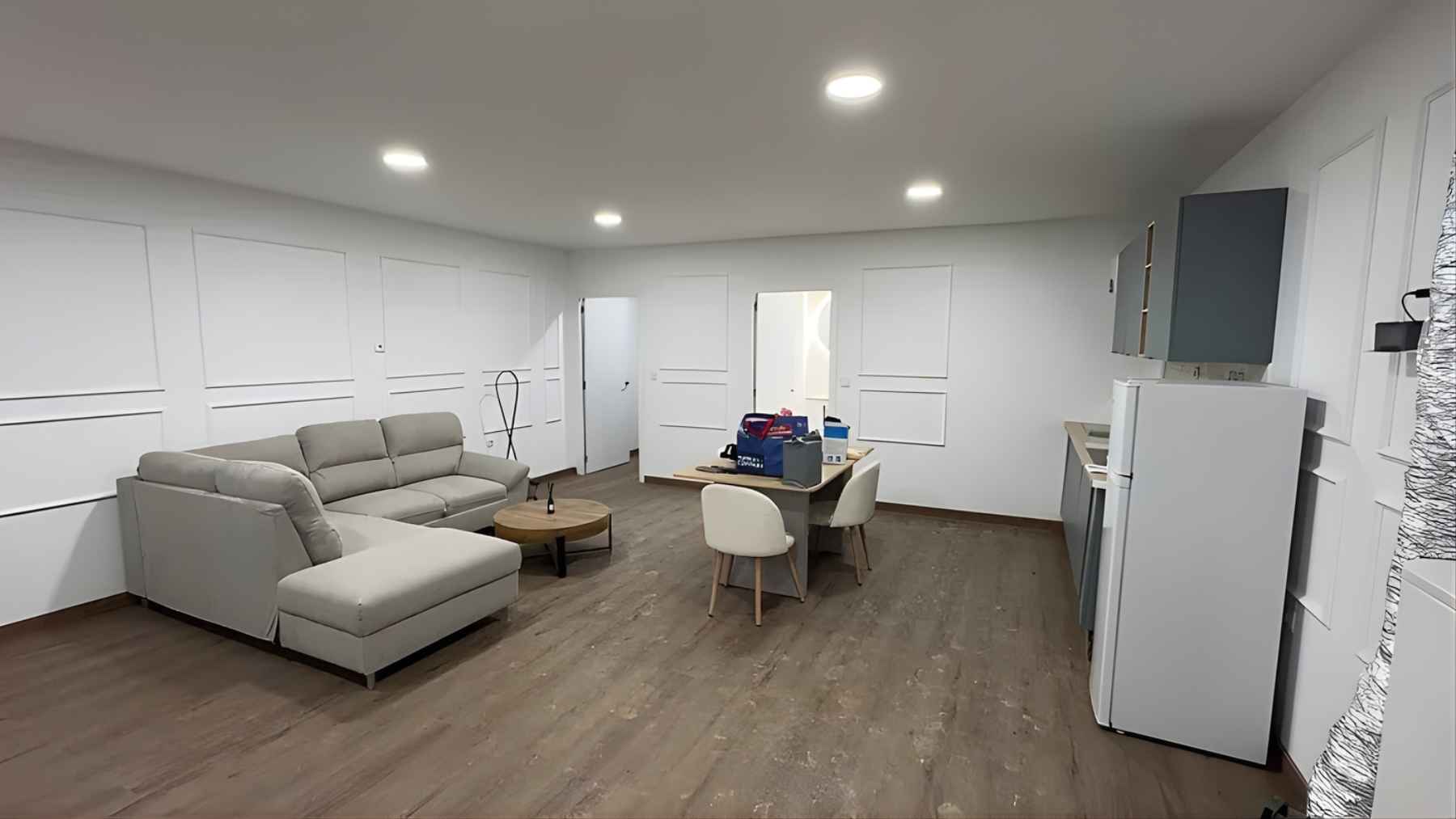 Interior of a private VIP bunker with a living area, seating, dining table, and kitchenette designed for emergency shelter.