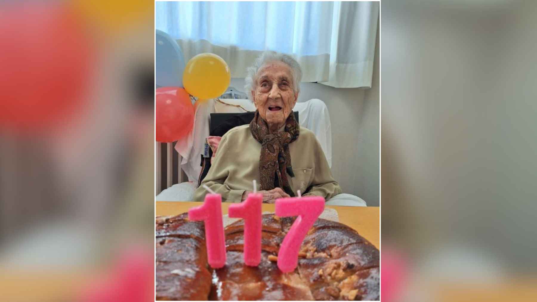 Maria Branyas Morera celebrating her 117th birthday with pink candles, balloons, and a cake in front of her