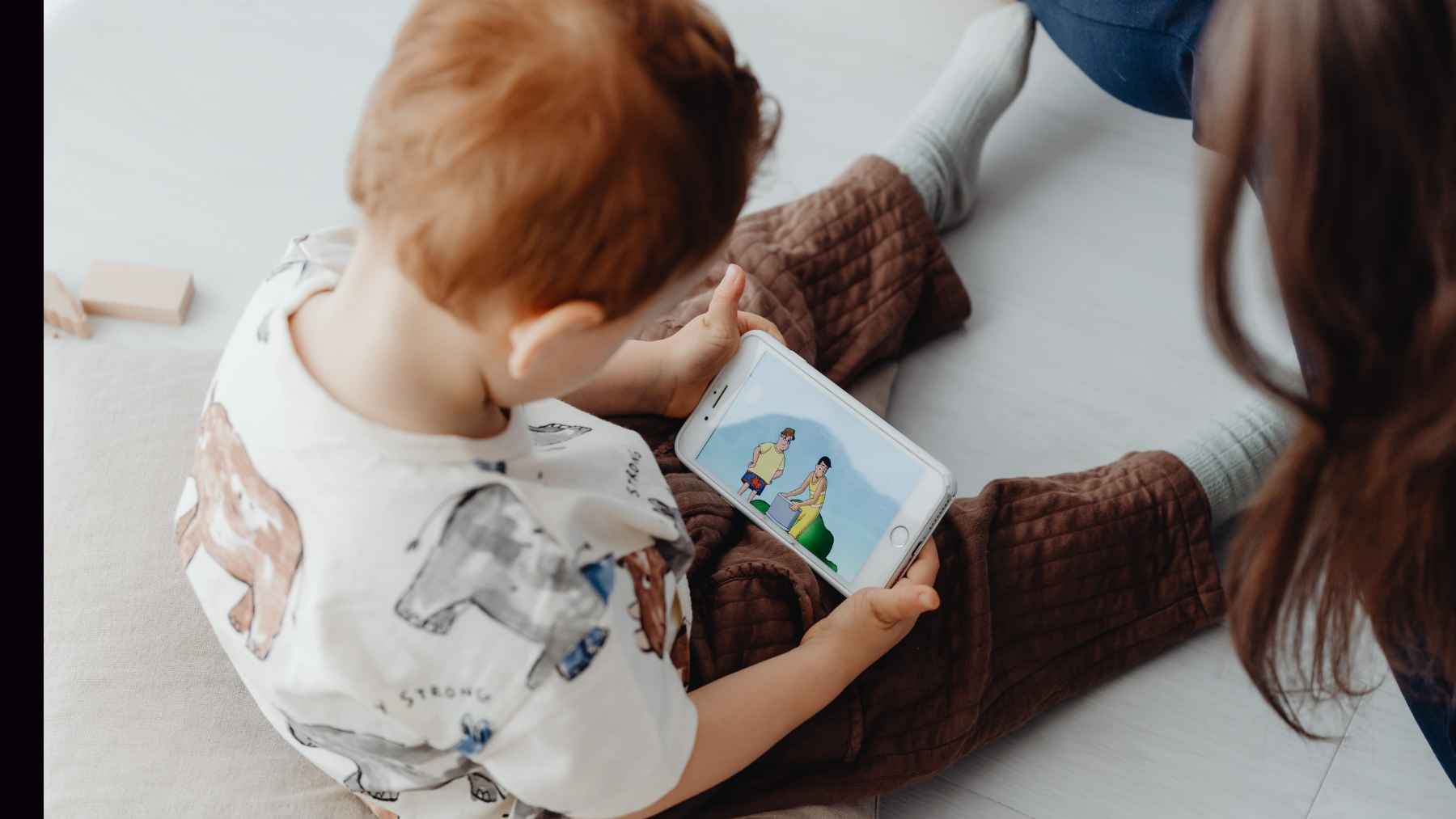 Baby holding a smartphone or tablet, illustrating research on early screen exposure and its potential effects on brain development.