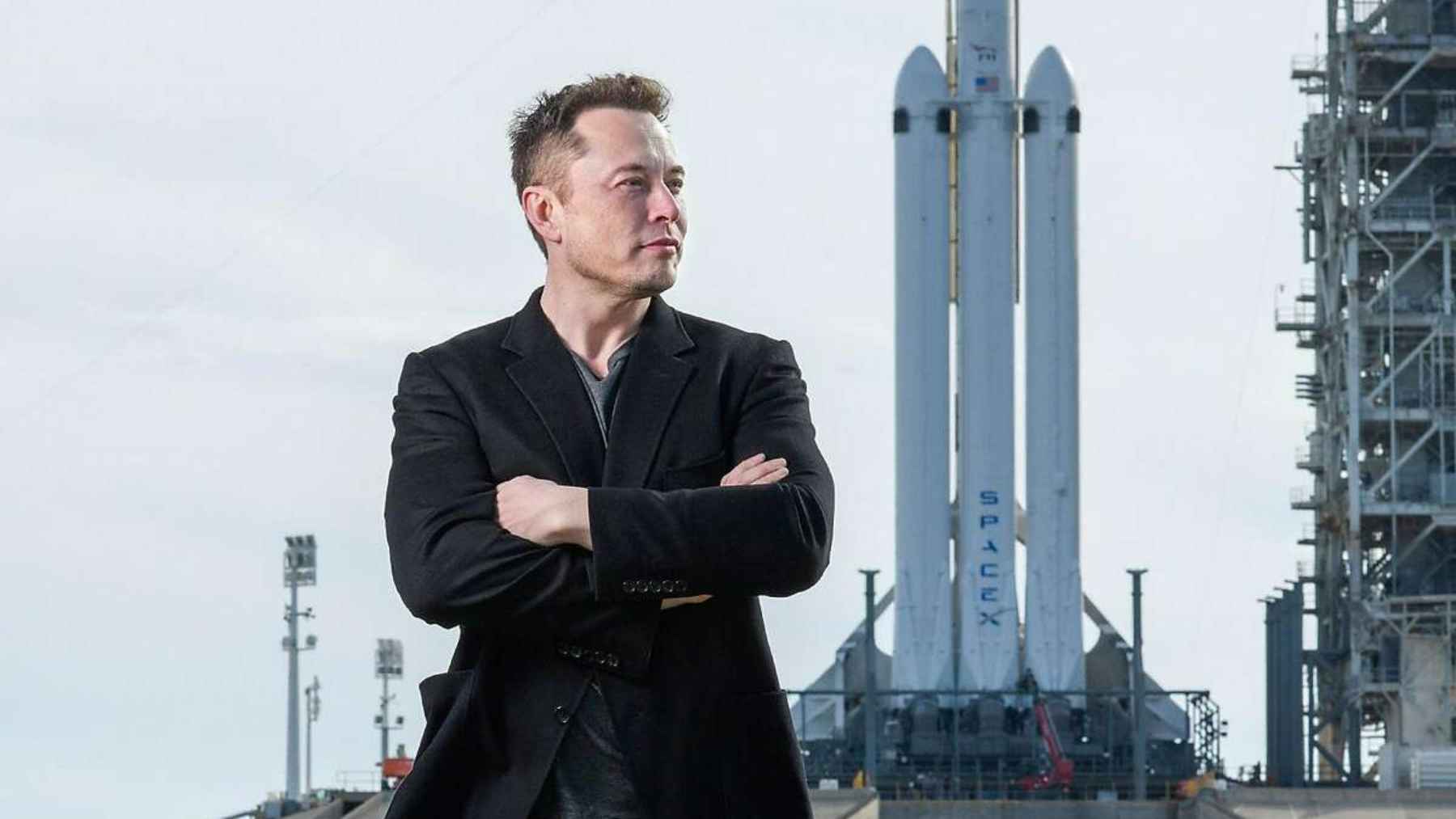 Elon Musk standing in front of a SpaceX rocket on a launch pad, illustrating the debate over Moon and Mars settlement plans