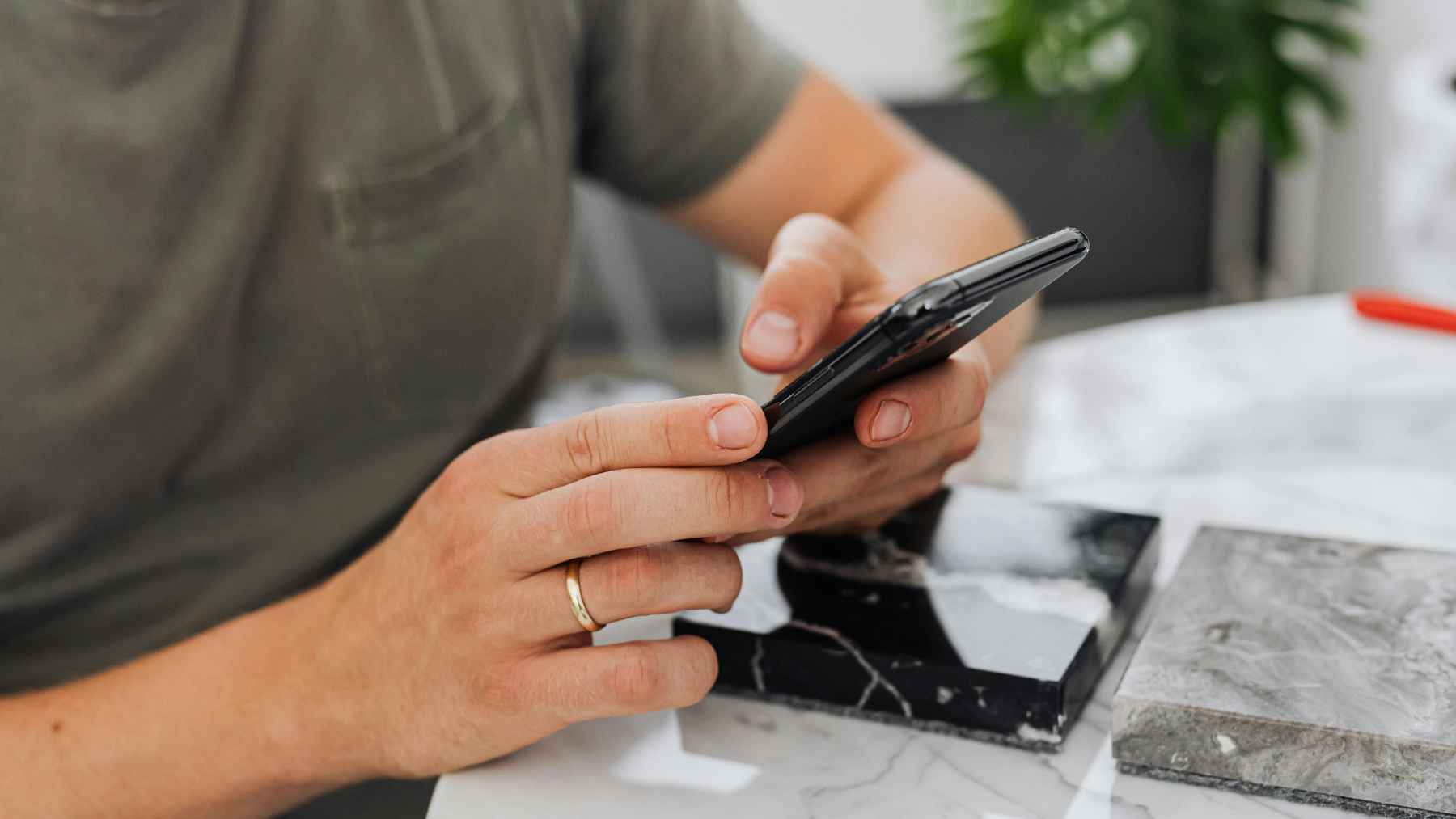 Person holding a smartphone in both hands at a table, illustrating the moment older phones lose software and security updates.