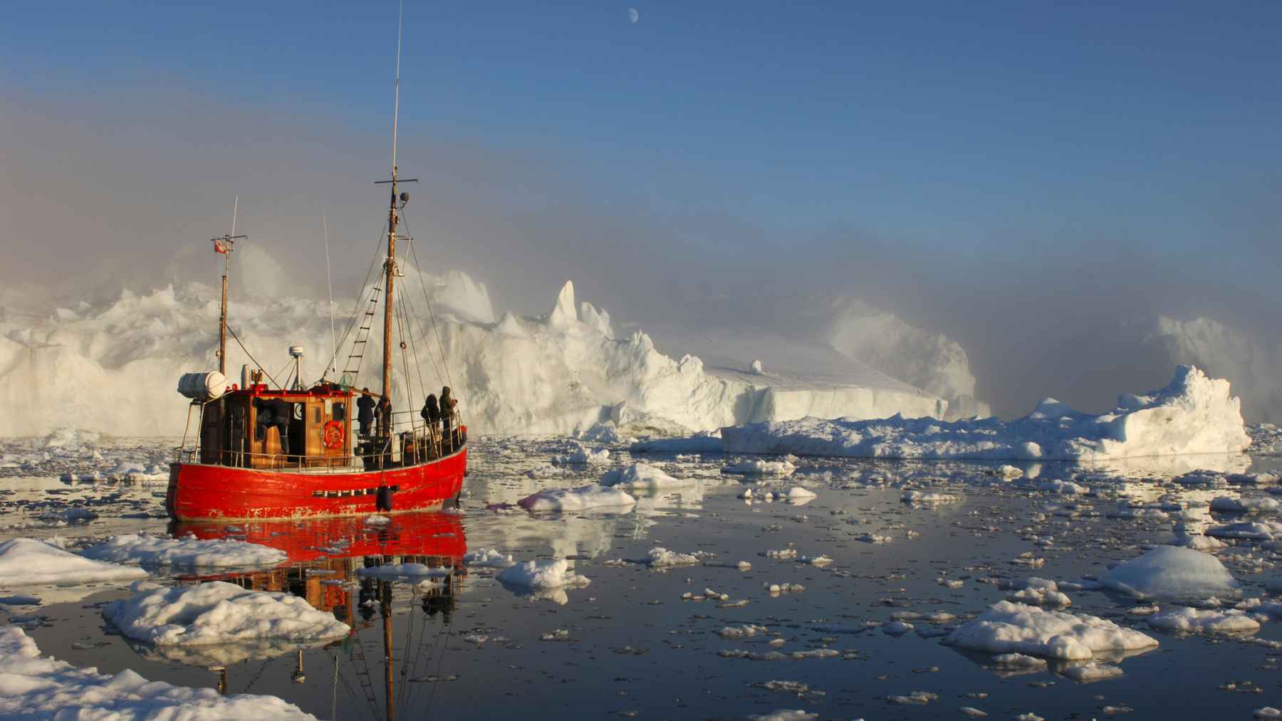 Red boat moving through icy Greenland waters near large ice formations, illustrating the coastal regions affected by ice loss and sea-level change.
