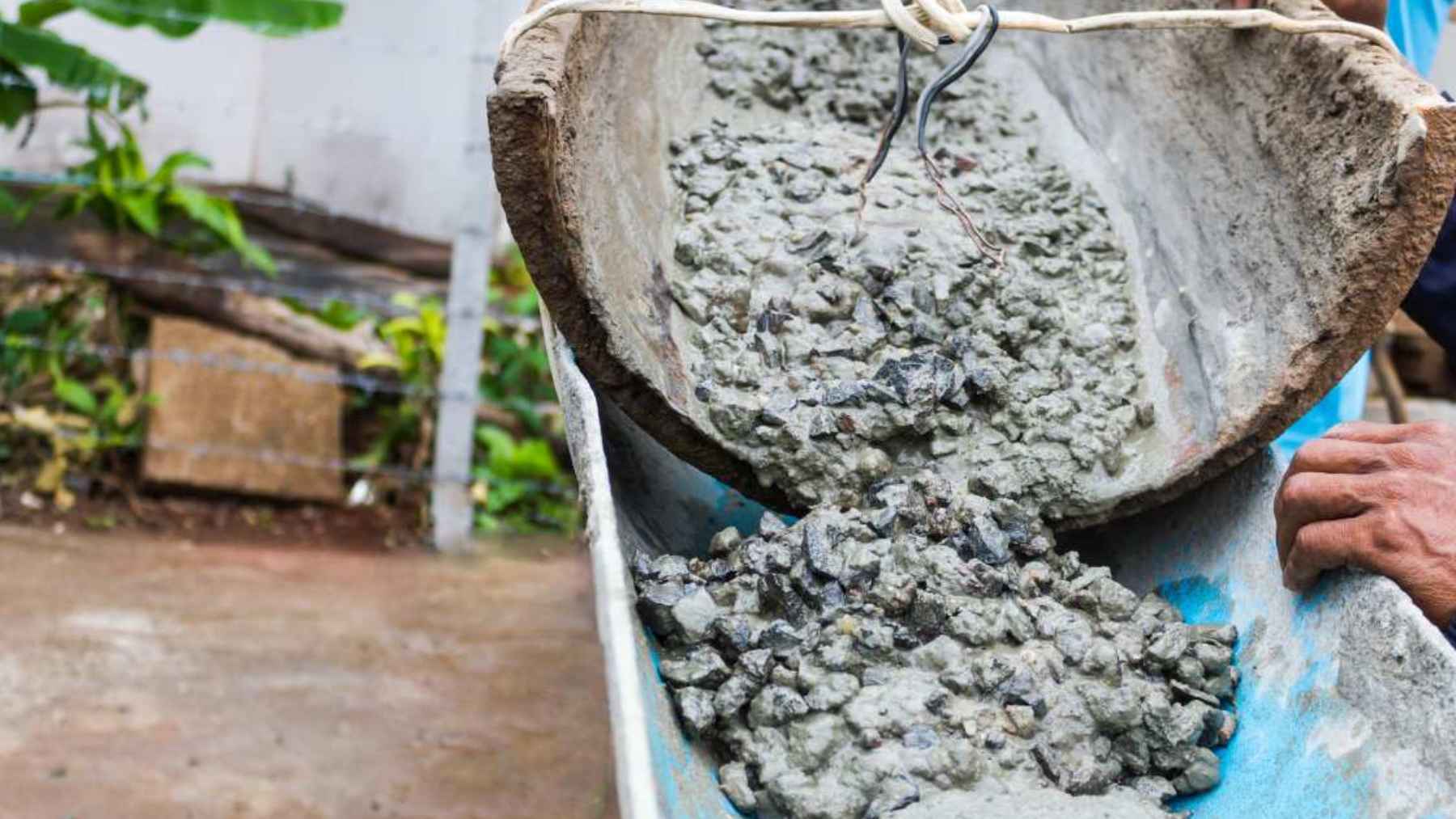 Wet magnetic cement mixture being poured during a wall-finish demonstration for movable no-drill storage