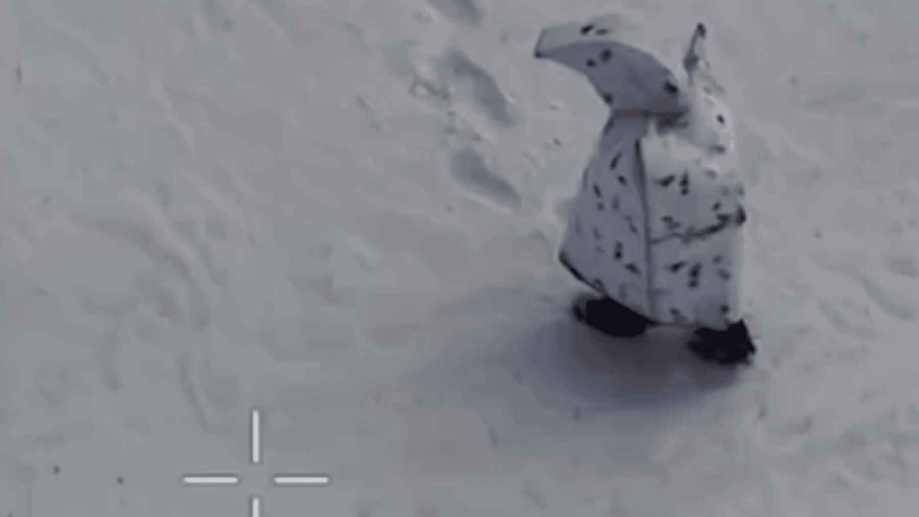 Russian soldier wearing experimental white “penguin” winter camouflage suit moving across a snowy field in Ukraine during drone surveillance.