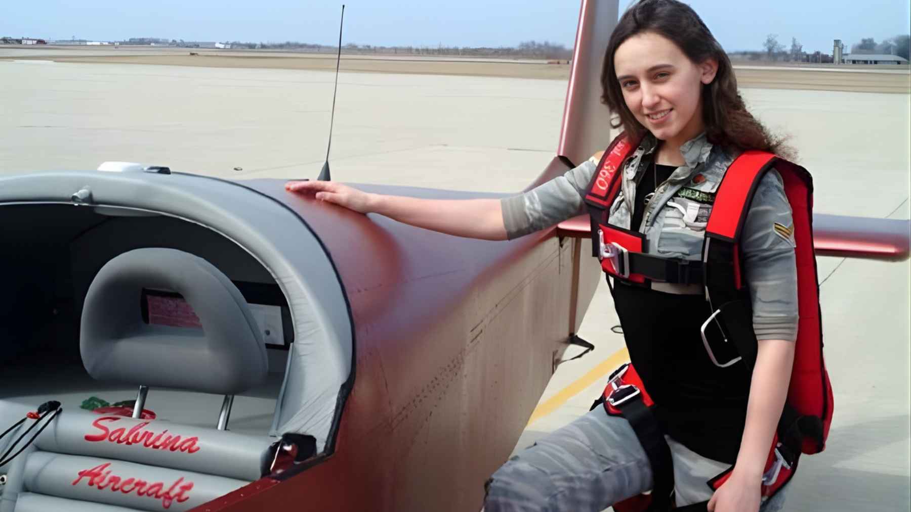 Young Sabrina Gonzalez Pasterski posing beside a small aircraft she helped rebuild, illustrating her early passion for aviation.