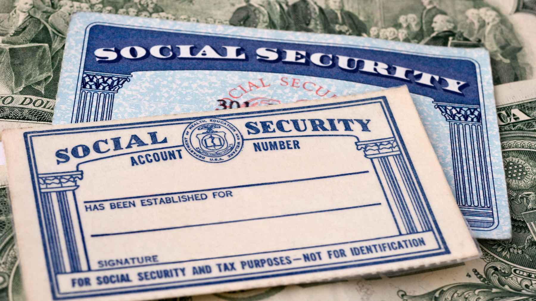 Social Security cards placed over U.S. dollar bills, illustrating retirement benefits and savings concerns for Americans turning 65.