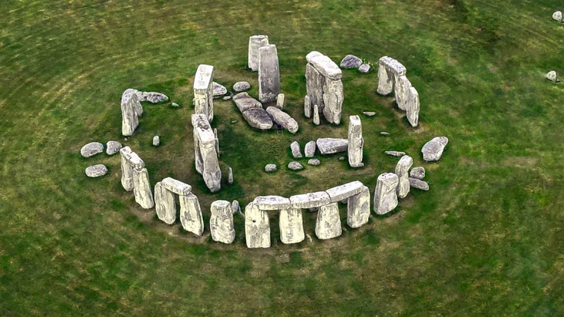 Aerial view of Stonehenge on green grass in southern England, showing the circular arrangement of the ancient standing stones.