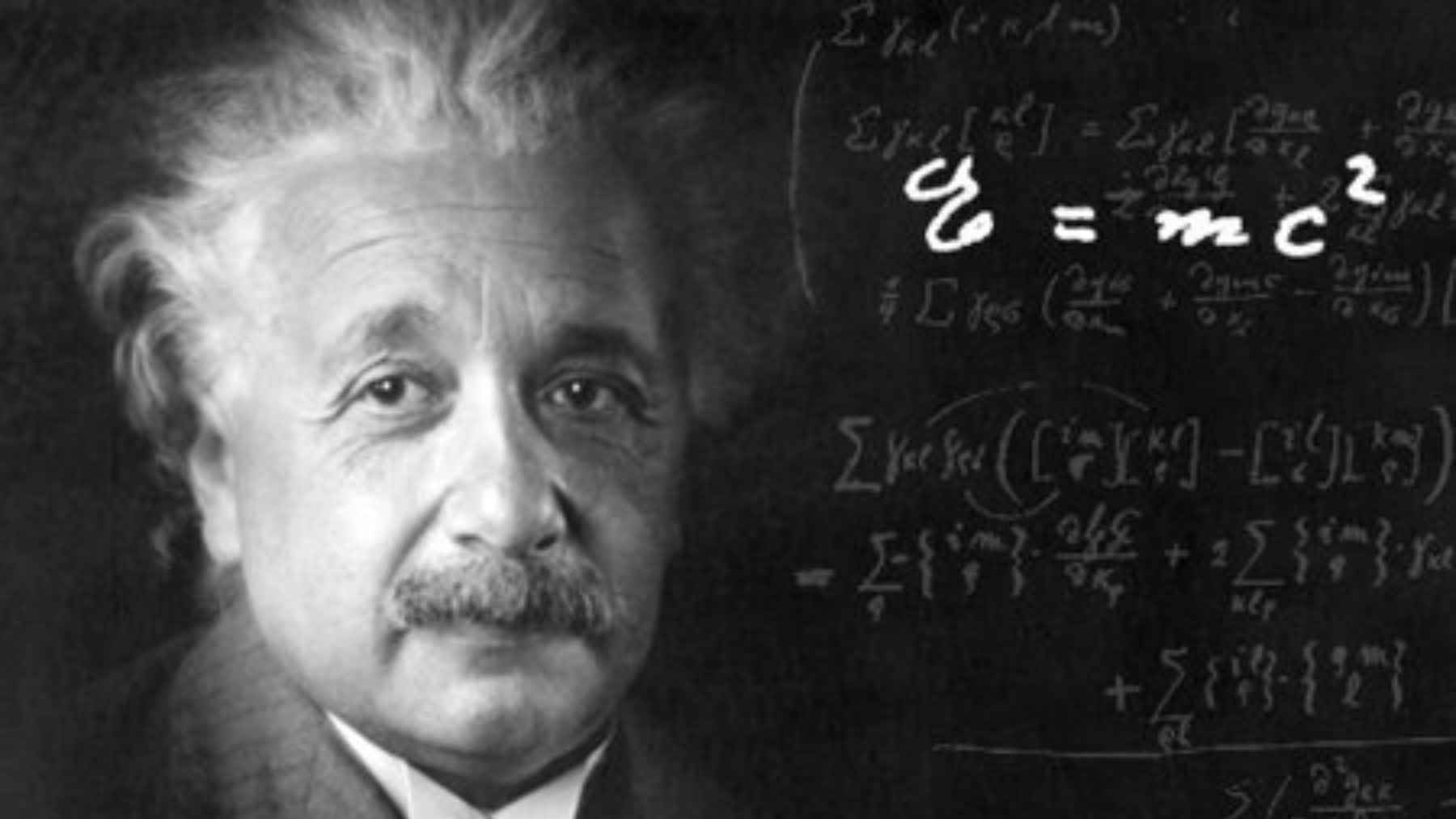 Portrait of Albert Einstein with physics equations on a blackboard, including the mass energy equivalence formula