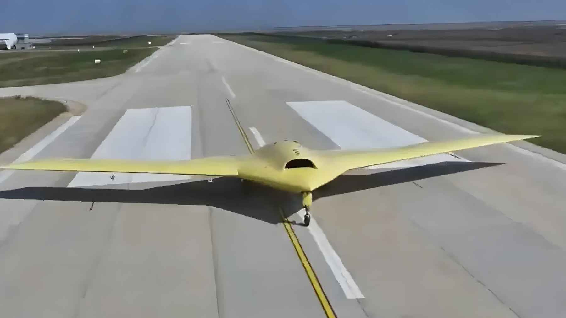 A yellow-primed Chinese CH-7 stealth drone taxiing on a runway during its first autonomous flight test.