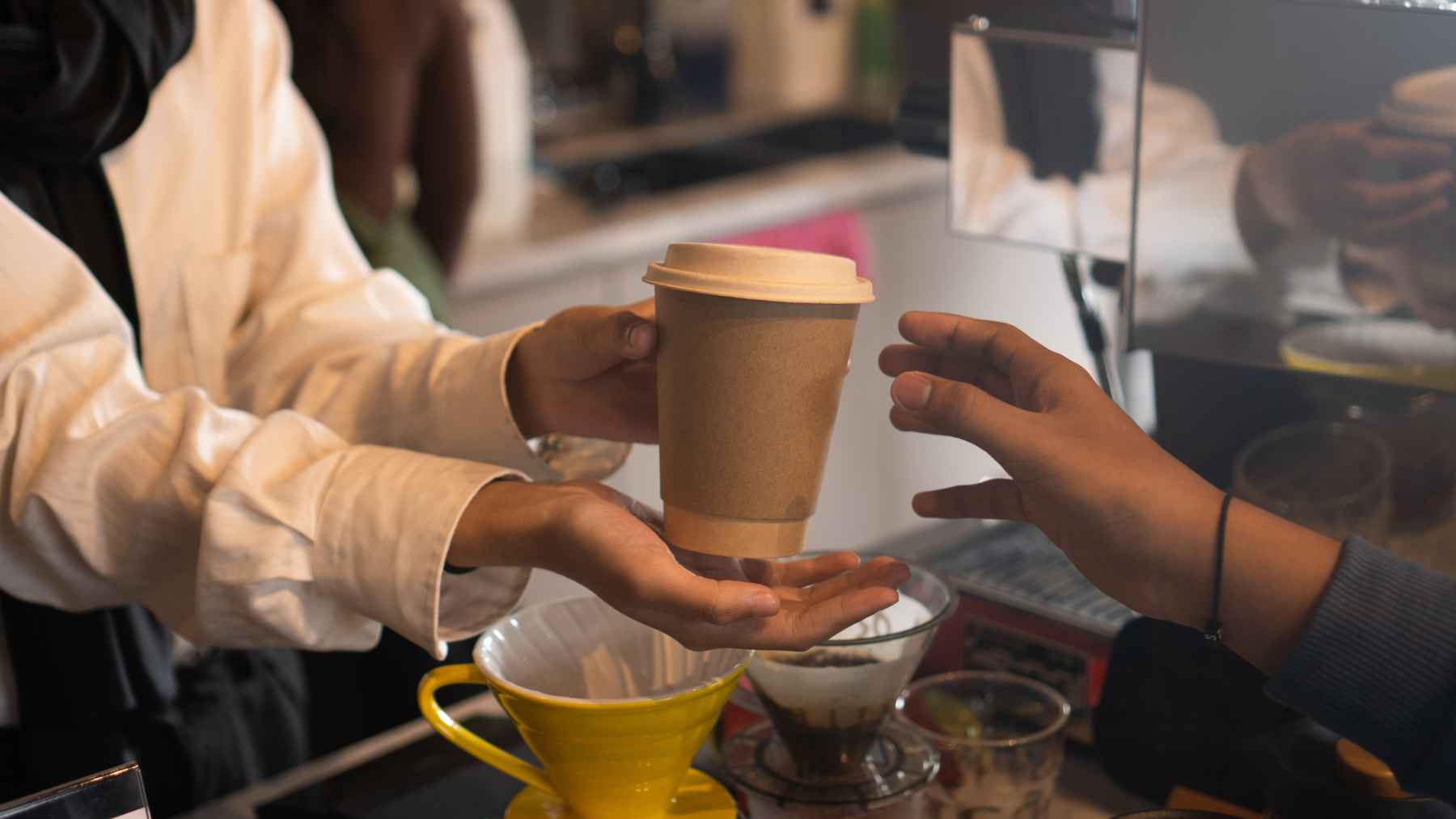 Barista handing a cup of coffee to a customer, illustrating research on coffee’s surprising effect on the gut microbiota
