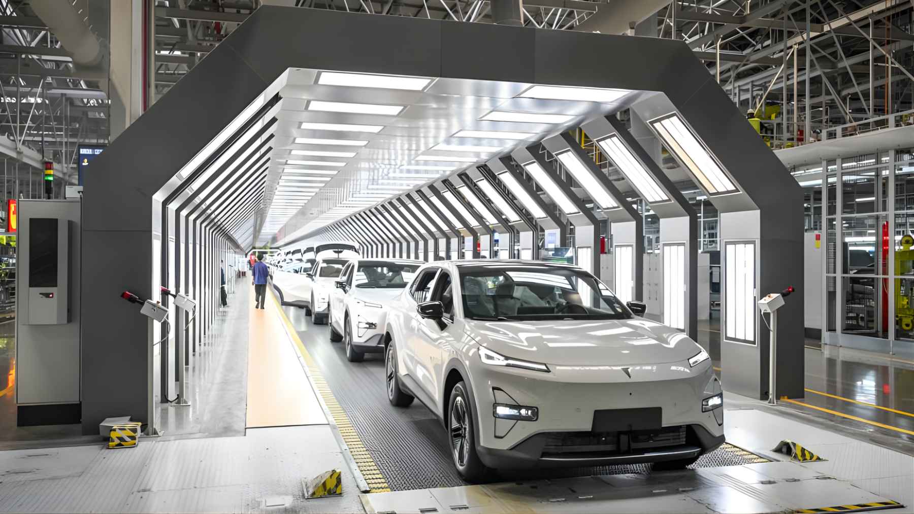 Electric vehicle on a final inspection line inside a modern car factory with bright overhead lighting and workers checking the vehicle.