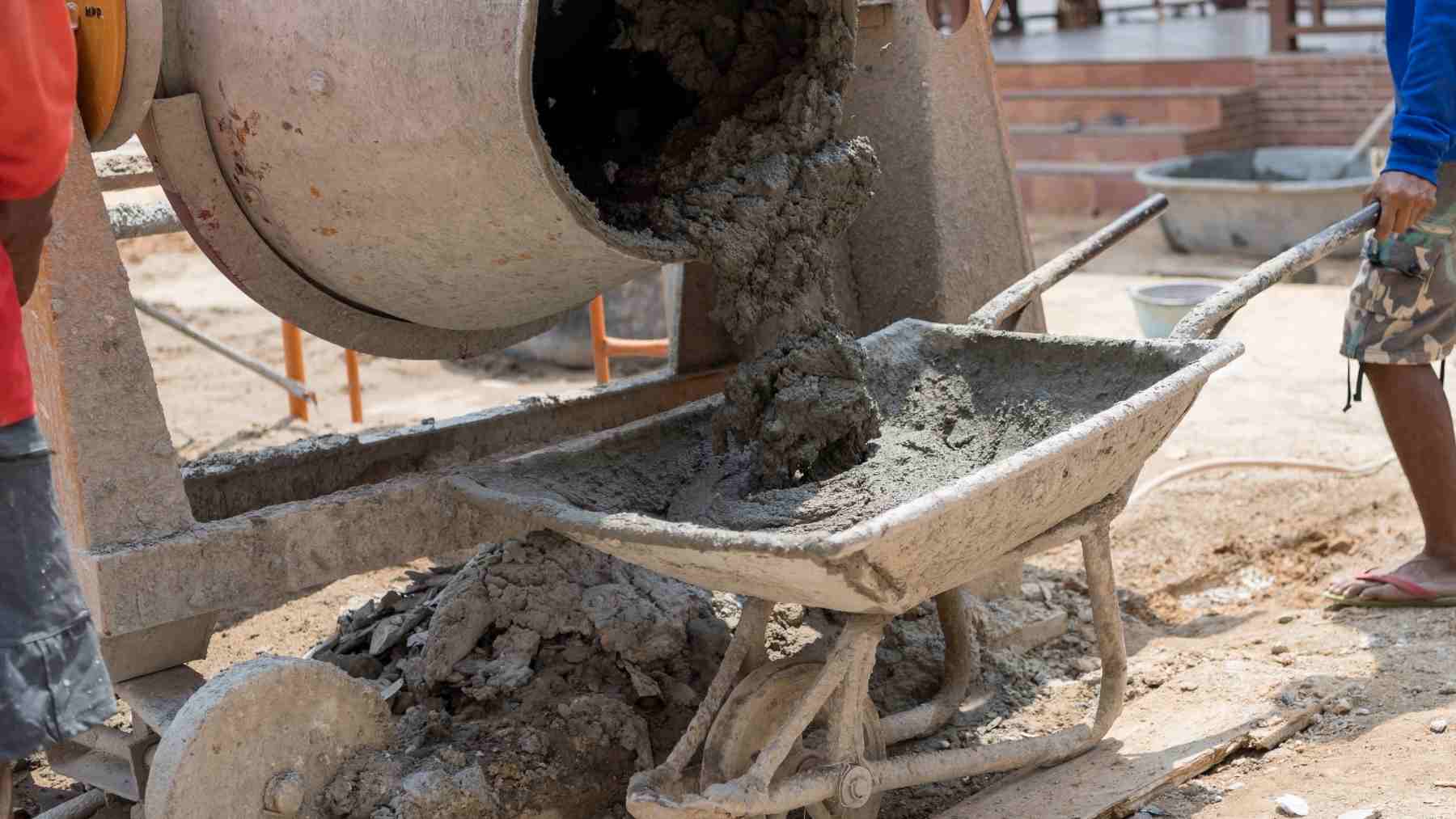 Concrete being poured from a mixer into a wheelbarrow, illustrating low carbon cement alternatives like algae biochar concrete.