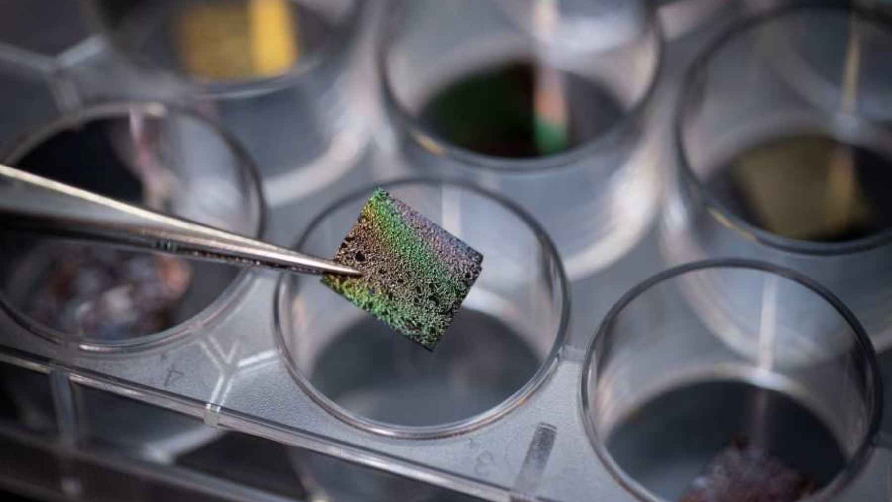Close-up of a lab-made cosmic dust sample held with tweezers during research on the origins of life’s chemical ingredients