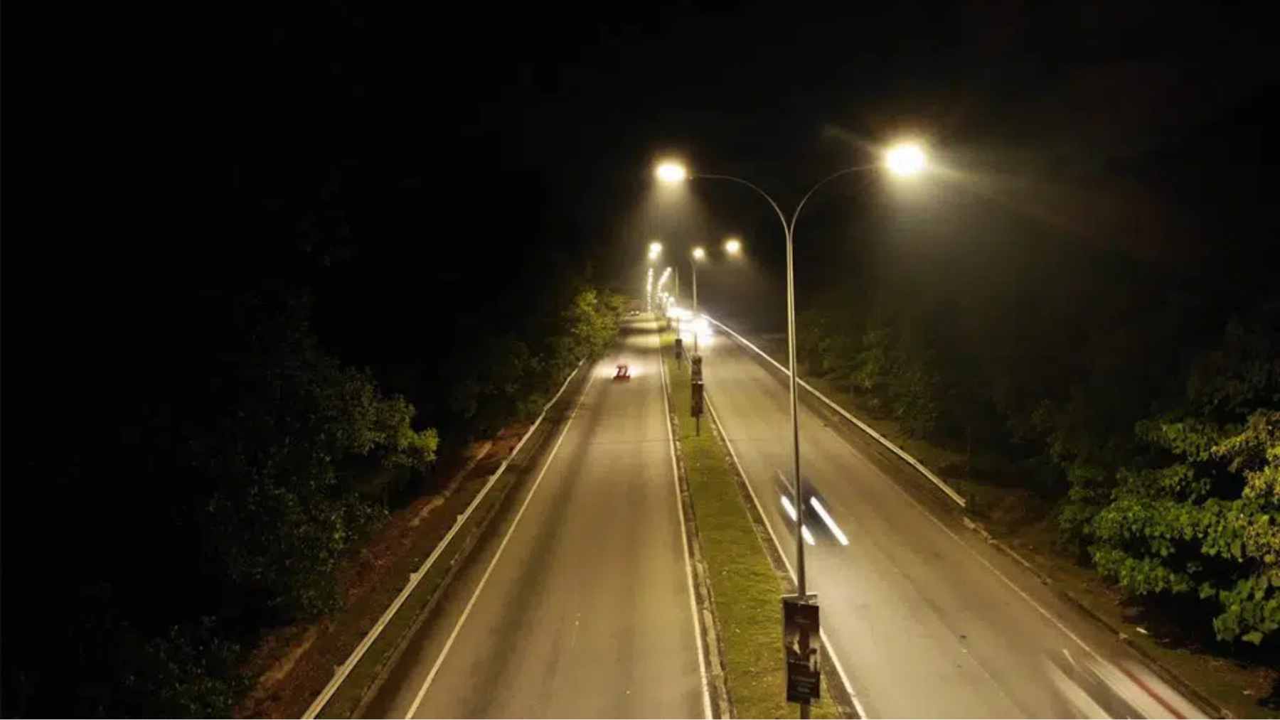 A dark roadway at night illuminated only by bright, glowing photoluminescent lane lines.