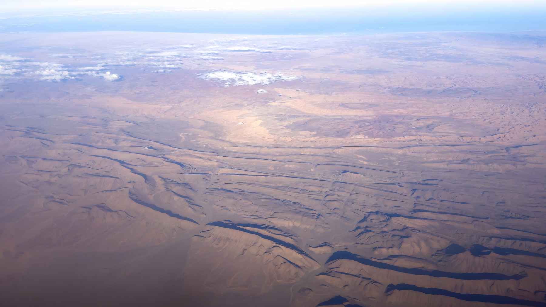 Aerial view of dramatic rock folds and desert ridges in Morocco’s Atlas Mountains.