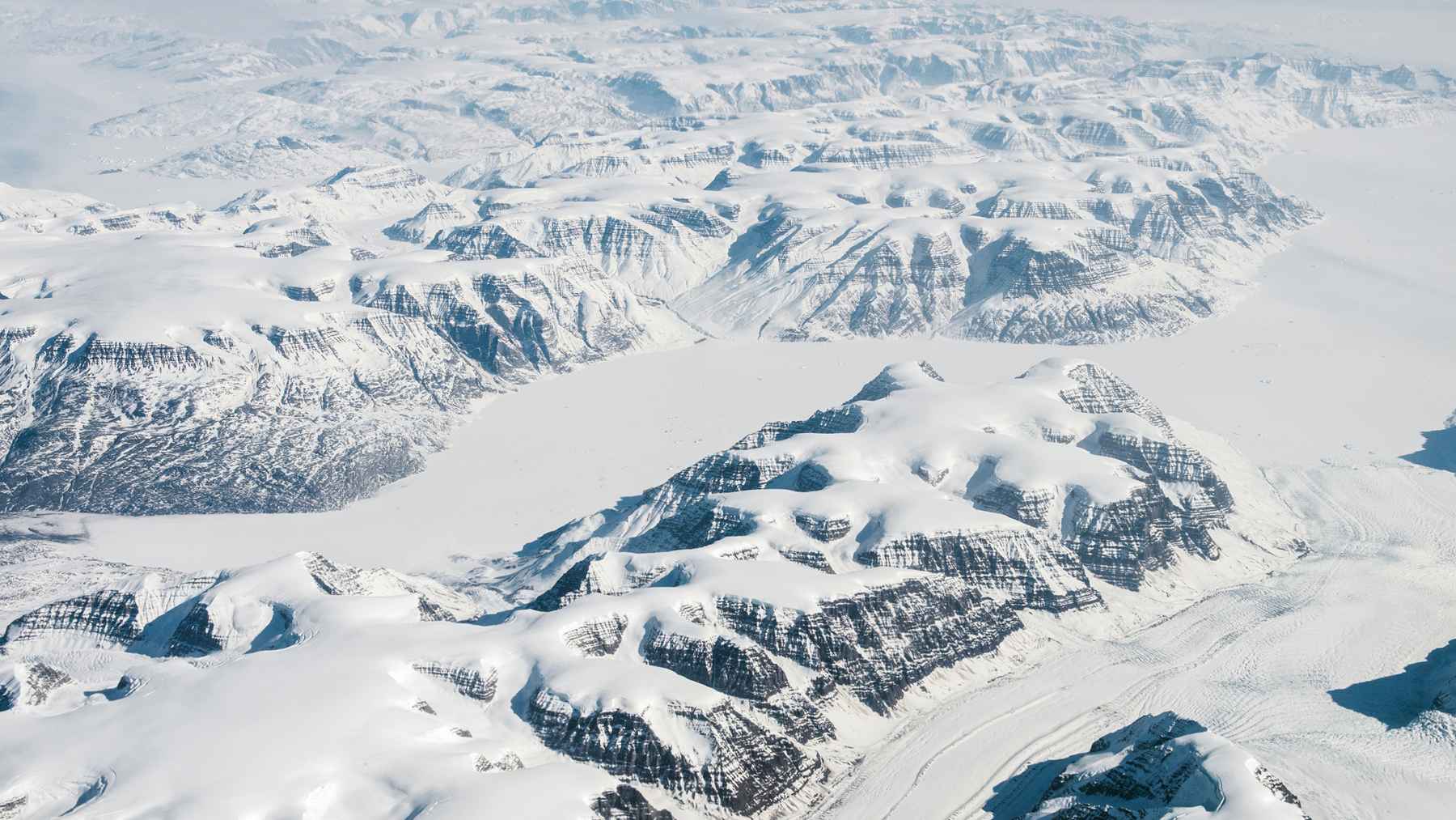 Aerial view of Greenland’s icy mountains and ice sheet near Camp Century, the Cold War base detected by NASA radar