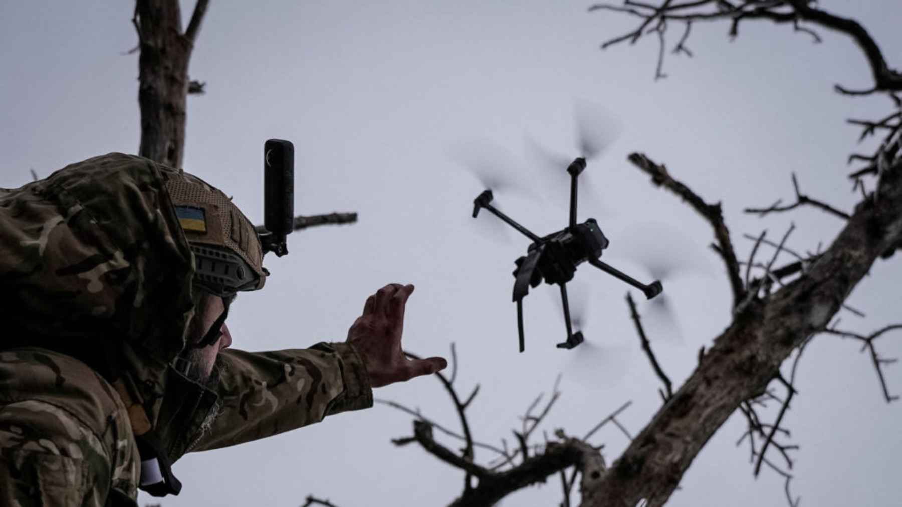 Ukrainian soldier operating a drone near a forested battlefield during the war with Russia.