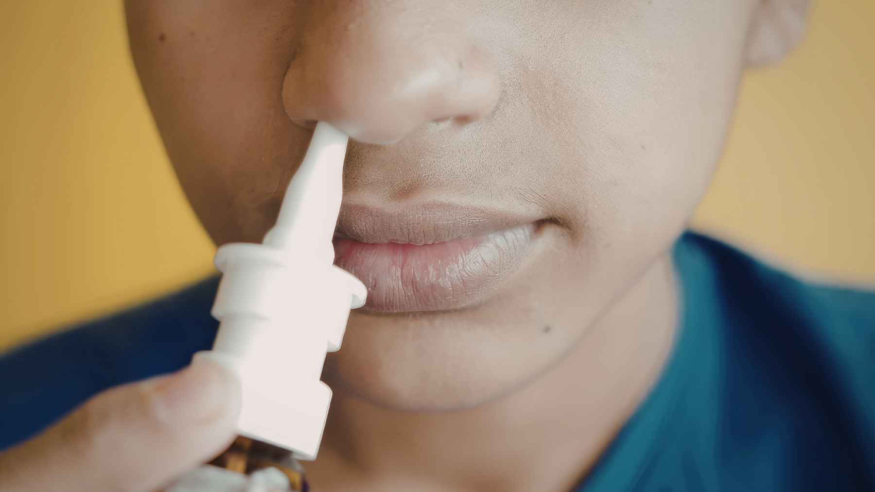Close-up of a person using a nasal spray linked to research on a universal vaccine for respiratory infections and allergies