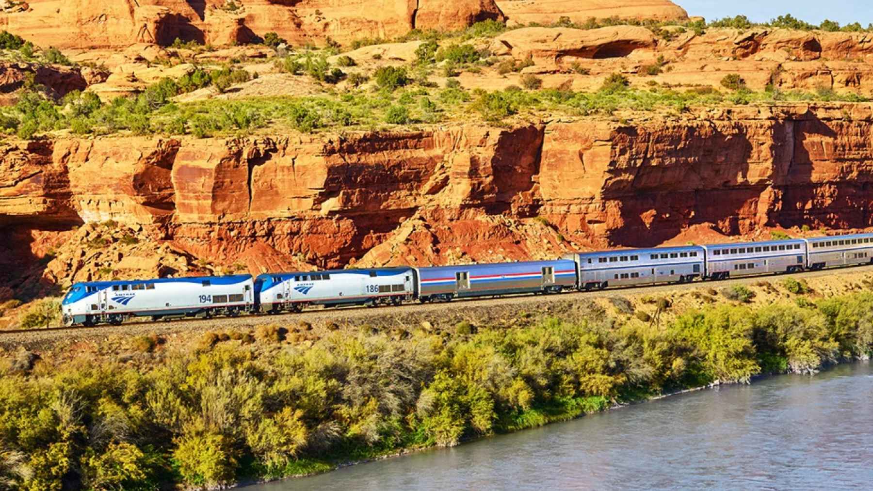 Amtrak California Zephyr traveling beside a river through red rock canyons in the American West