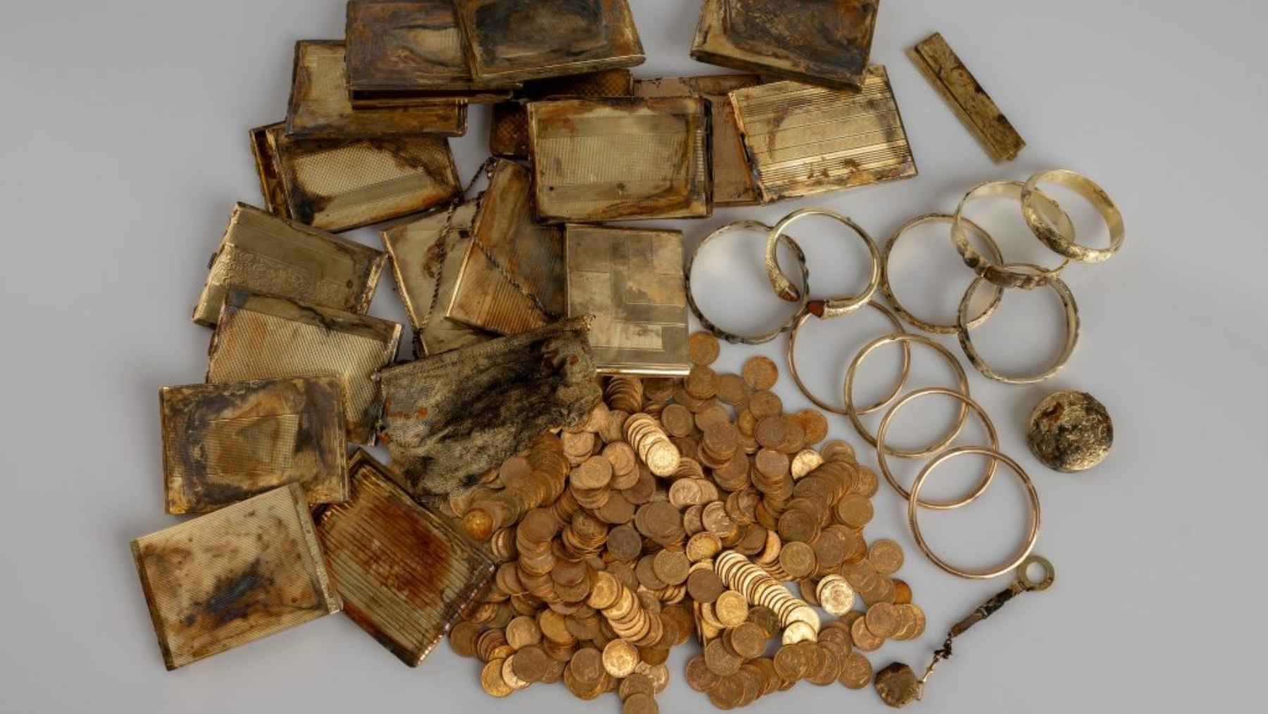 Gold coins, bracelets, metal cases, and personal objects from a buried Czech treasure hoard found by hikers.
