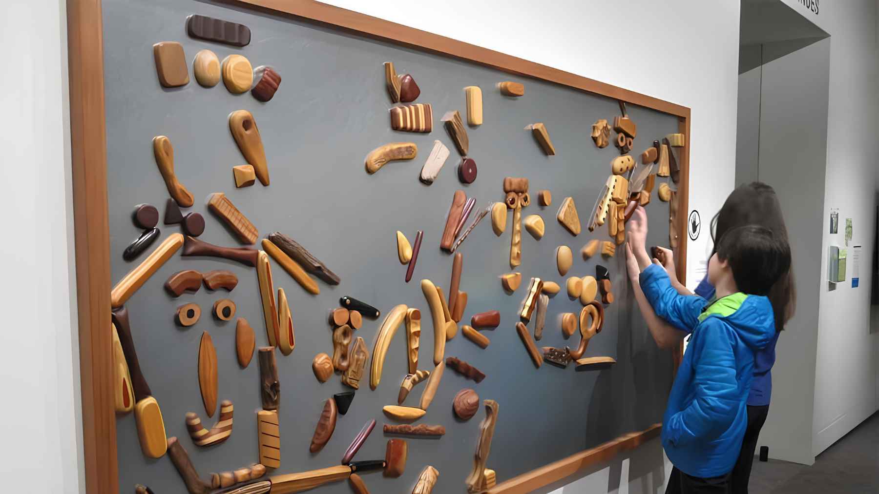 ECOnews 1 Person placing wooden objects on a large magnetic wall display, illustrating how magnetizable surfaces can hold items without drilling.
