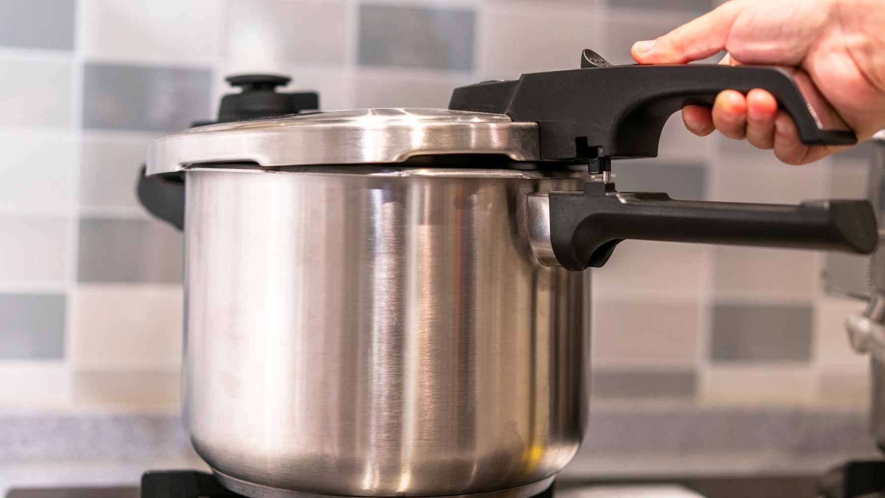 A pressure cooker on a stovetop with steam escaping from the pressure valve during a cooking experiment.